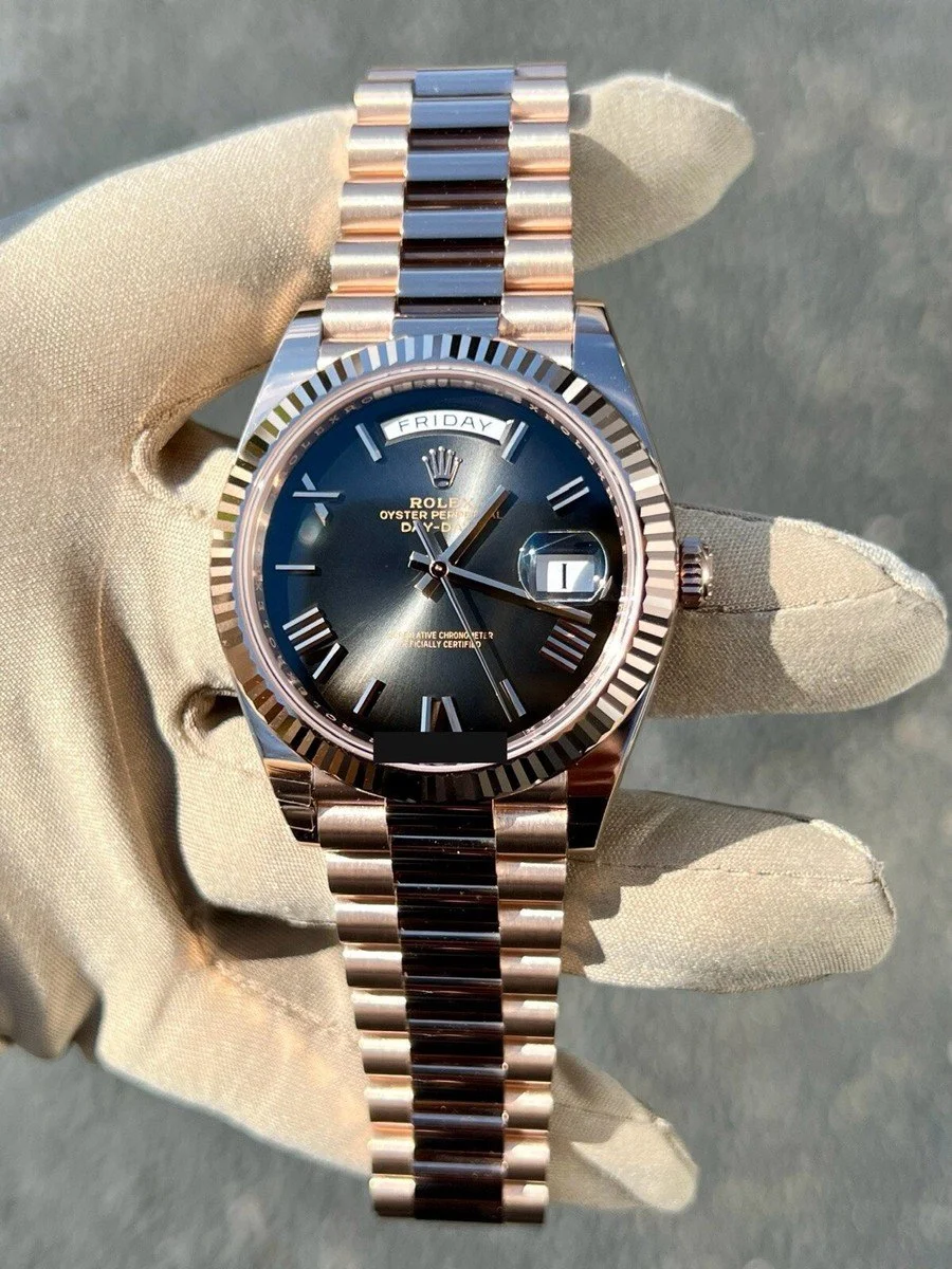 A person's gloved hand holding a Rolex Oyster Perpetual Day-Date watch with a black dial, Roman numeral markers, and a metallic band.