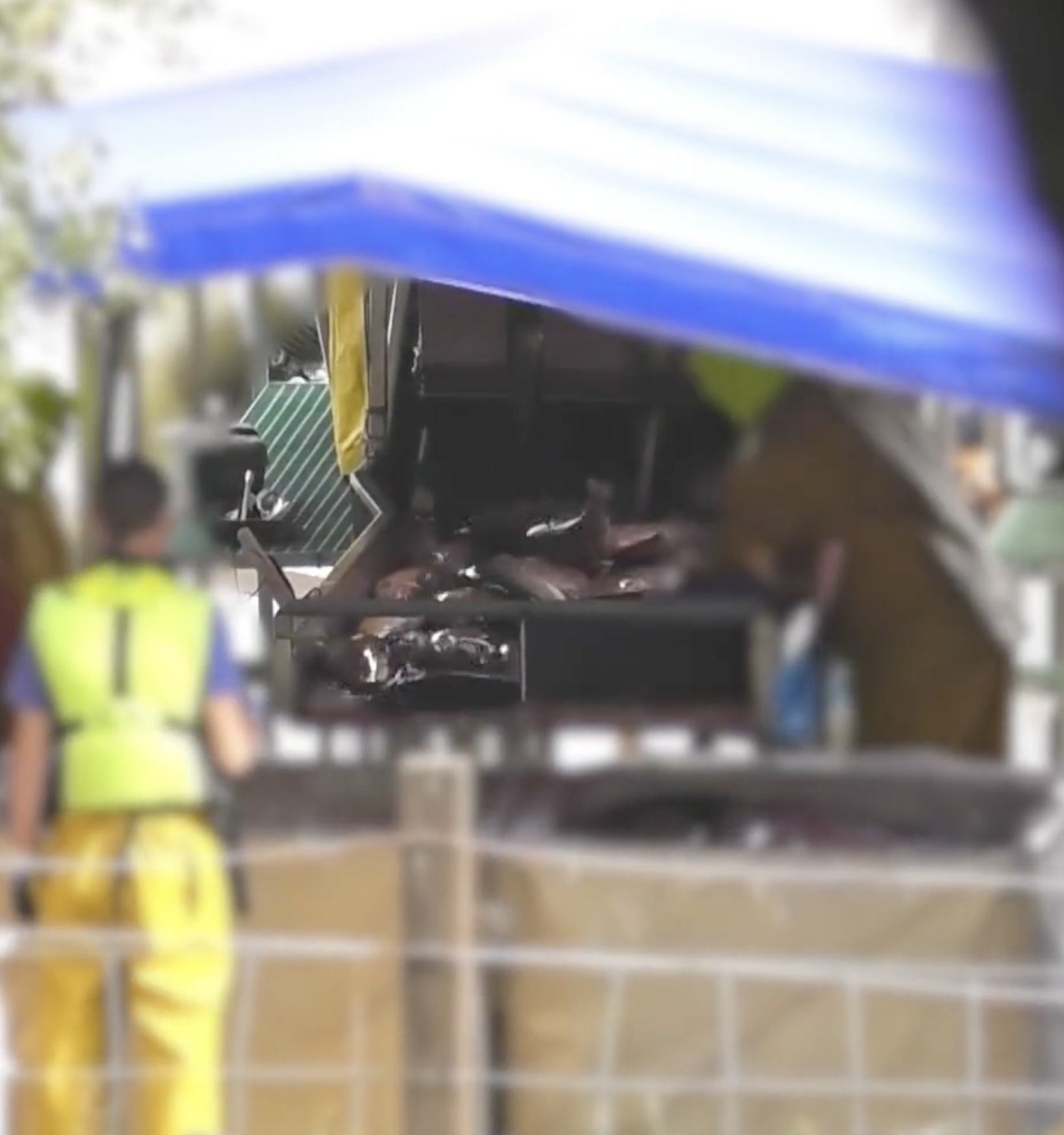 The image appears to show a blurry view of a corridor or hallway with some workers or personnel in yellow vests, possibly involved in construction or maintenance, passing by or standing along the sides. There are various structural elements and equipment, but the image quality makes specific details unclear.