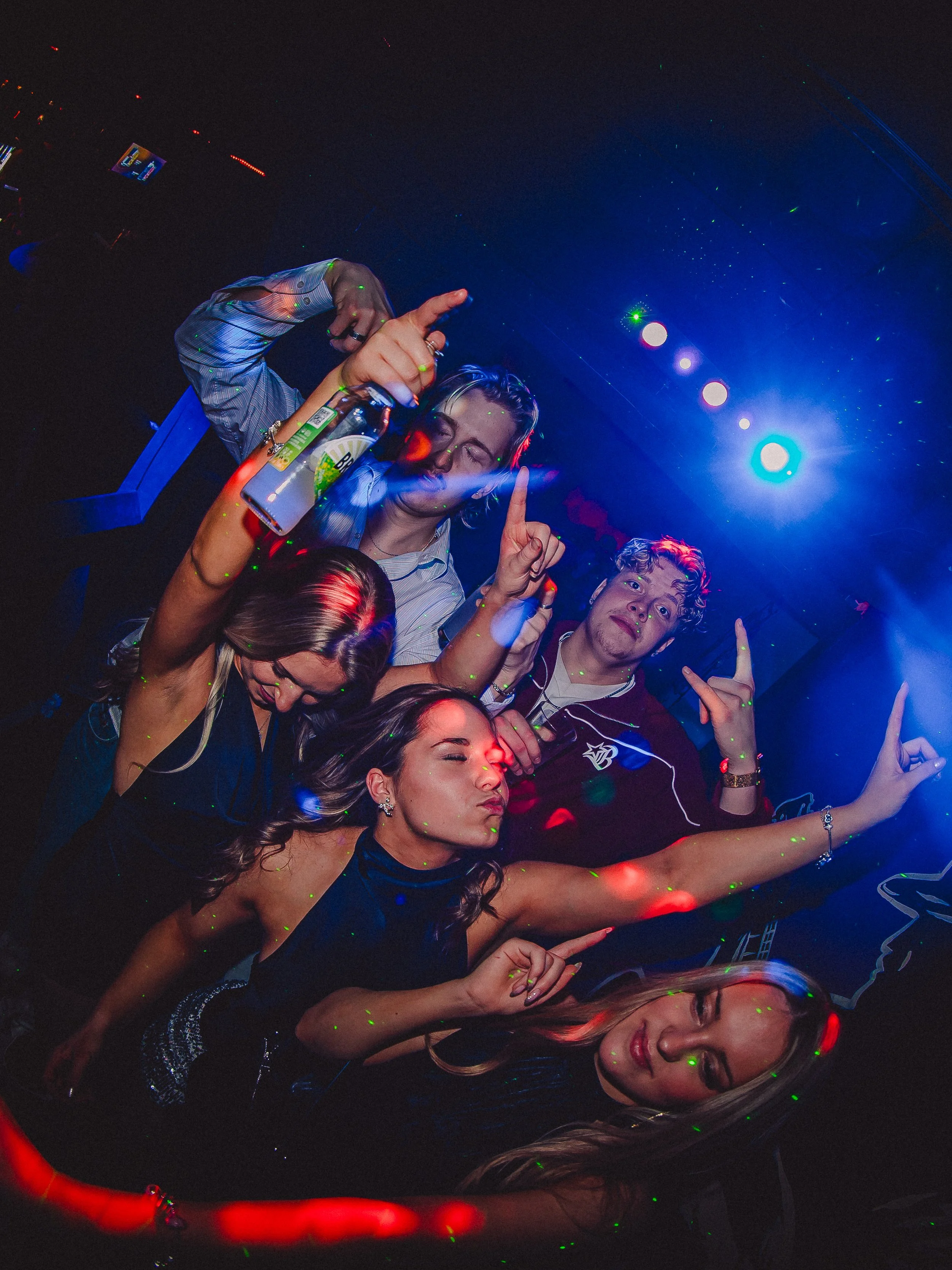 Group of people dancing and having fun at a nightclub with colorful lights and laser effects