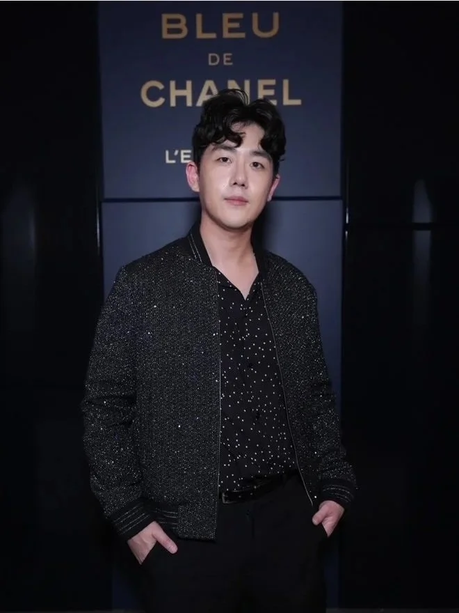 Brute Choi wearing a glittery jacket and a black shirt with white polka dots, at a Bleu De Chanel fragrance launch event.