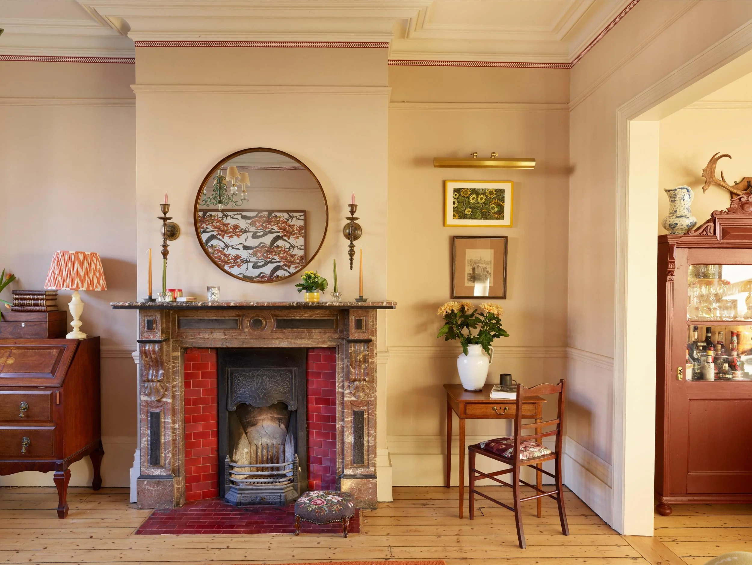 Living room corner with fireplace, mirror, framed art, potted plant, chairs, and various decorative items.