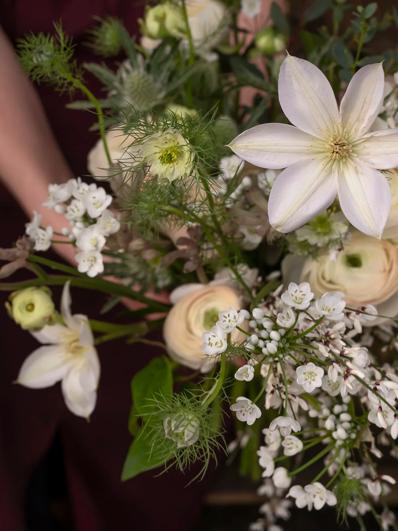 Close-up of a bouquet of white flowers, including large star-shaped blooms, small clusters of tiny white flowers, and green foliage.