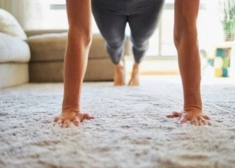 Person doing push-up on a carpet in a living room