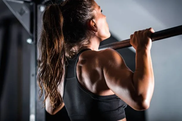 A woman doing a barbell exercise in a gym.
