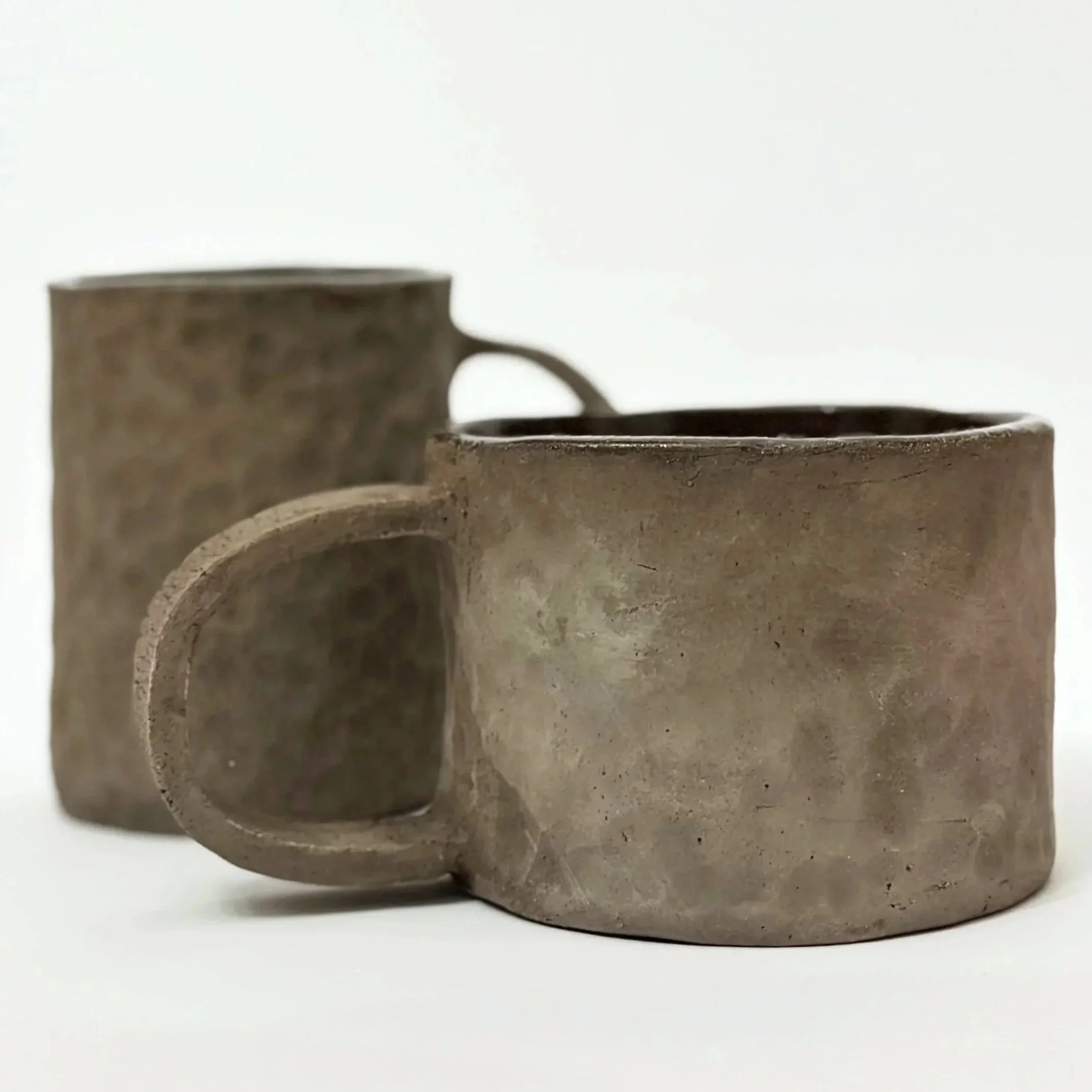 Tazza di ceramica di colore marrone con un manico, vista laterale.