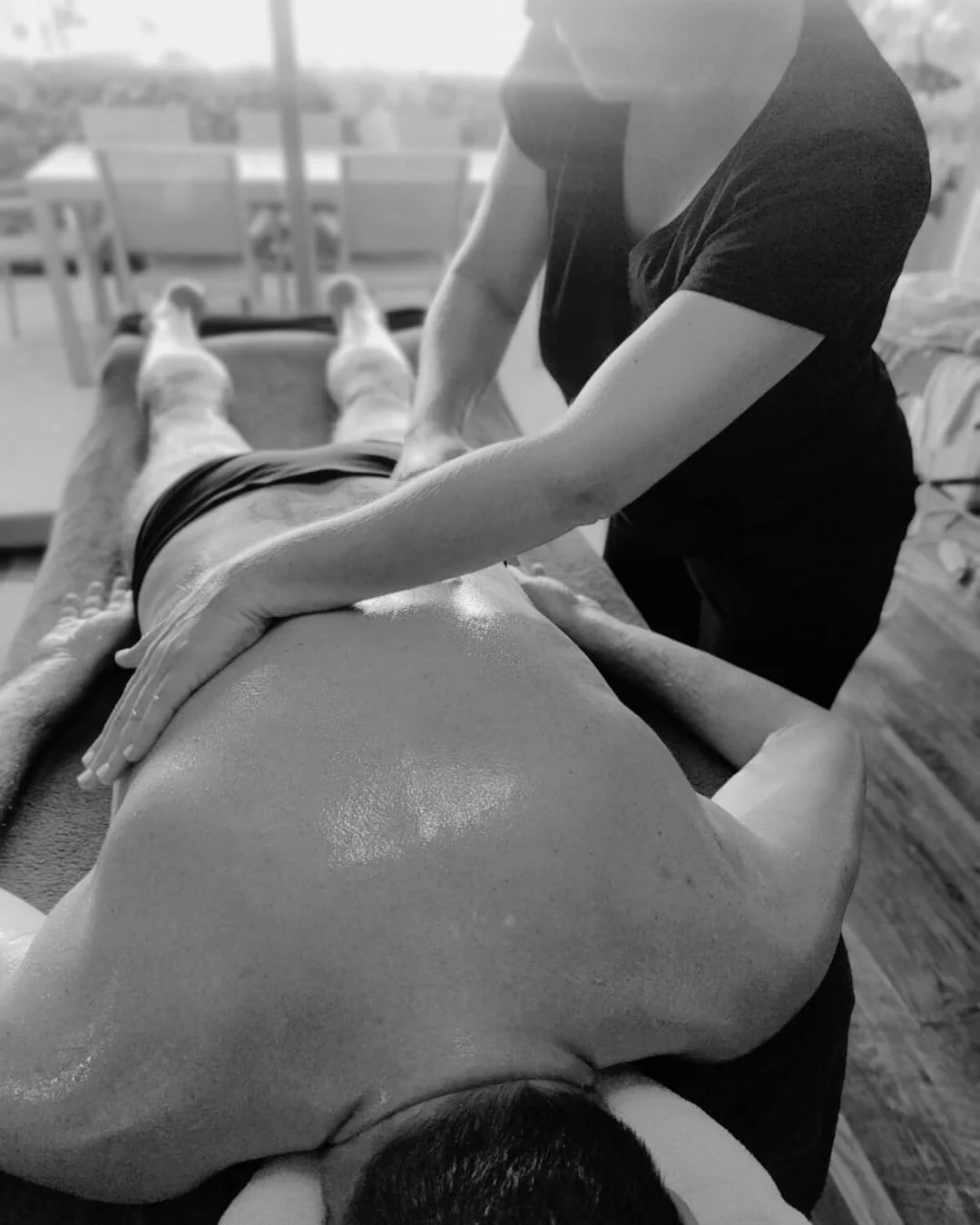Pratique de massage thérapeutique d'une personne allongée sur une table, avec un praticien qui applique une technique de massage sur son dos.