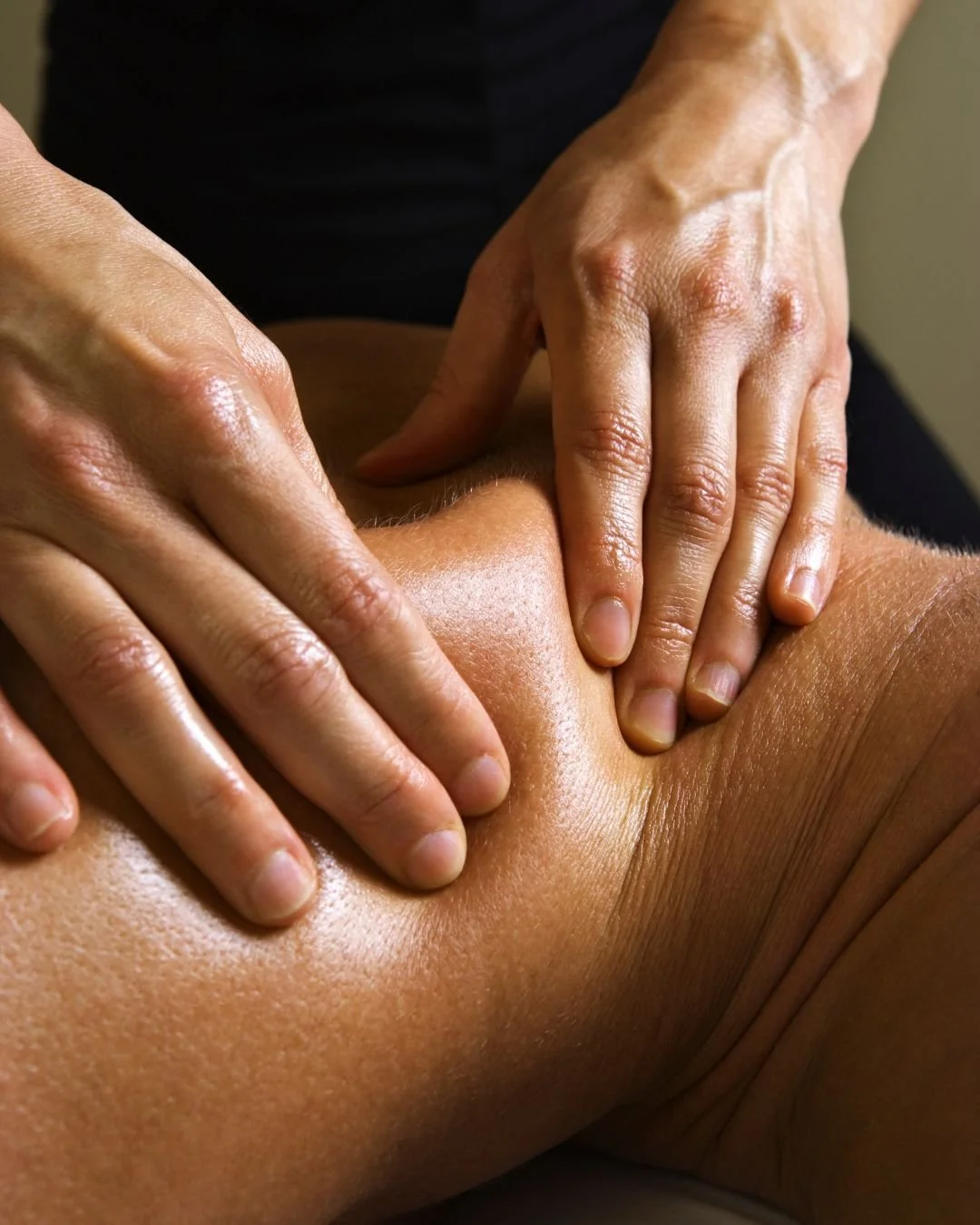 Une personne reçoit un massage sur la cuisse ou la hanche, des mains appliquant une pression ferme.