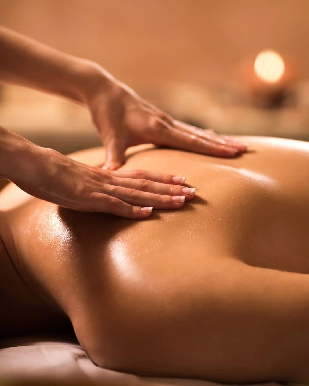 Une personne reçoit un massage sur le dos dans une ambiance chaleureuse et relaxante.