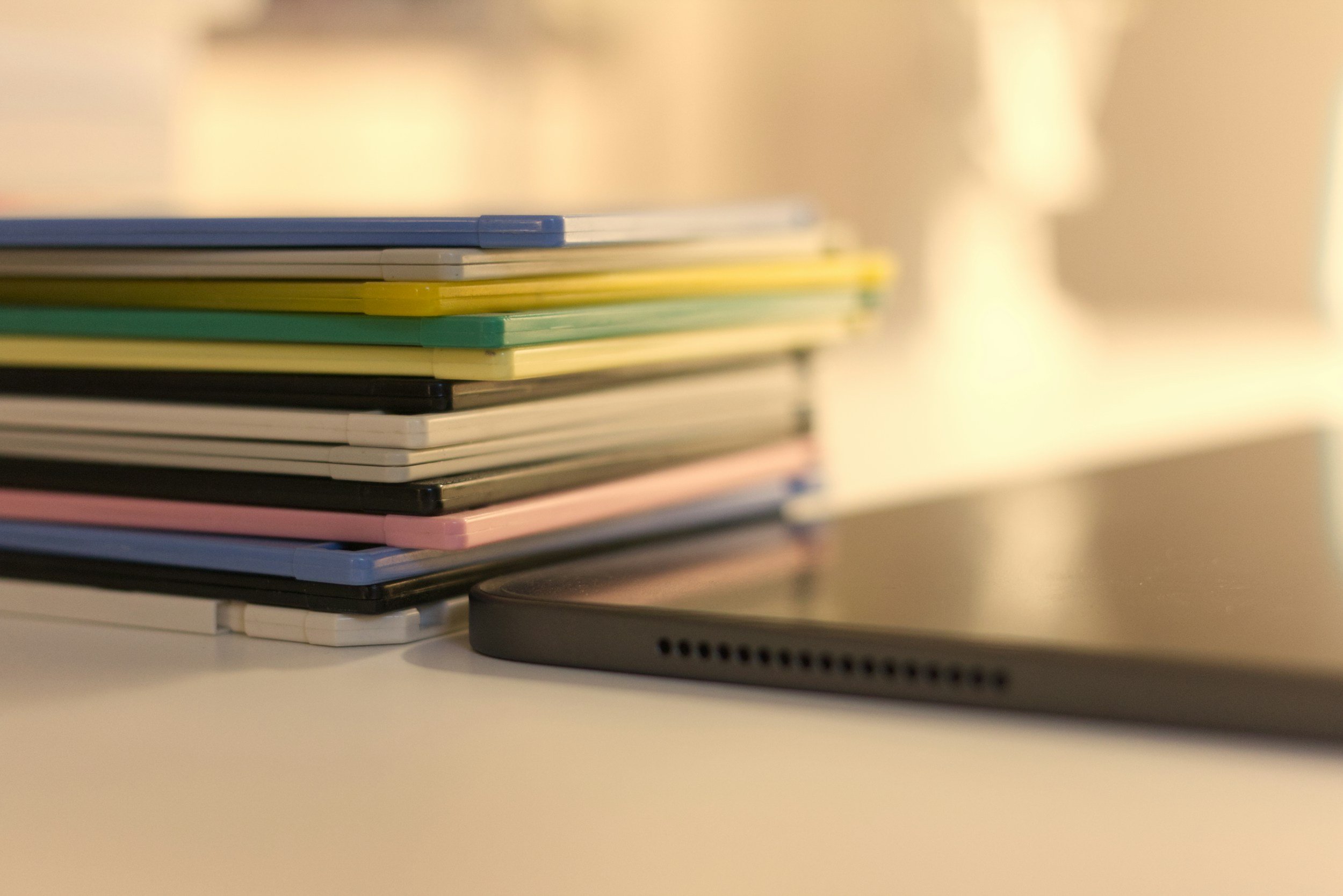 Stack of colorful portable electronic devices on a white surface, with a smartphone in the foreground.