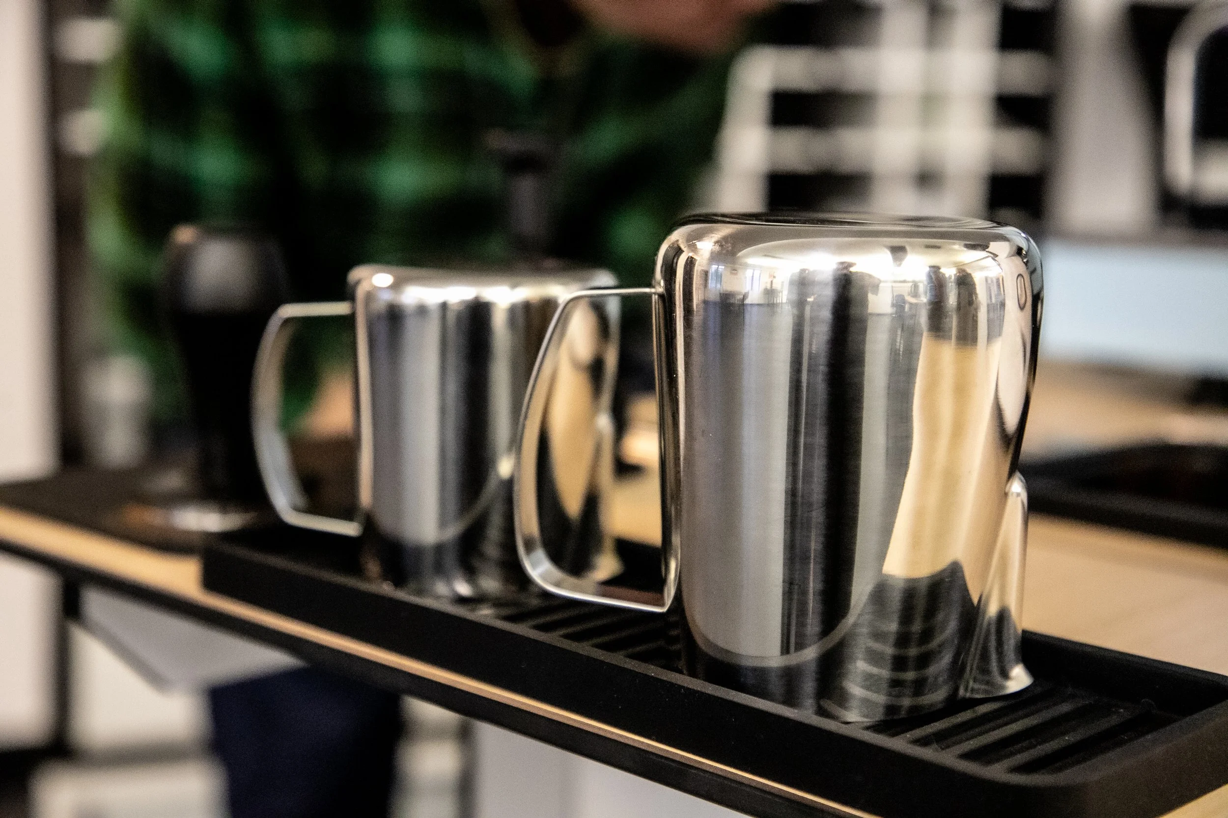 Metallic espresso cups on a black shelf against a blurred background