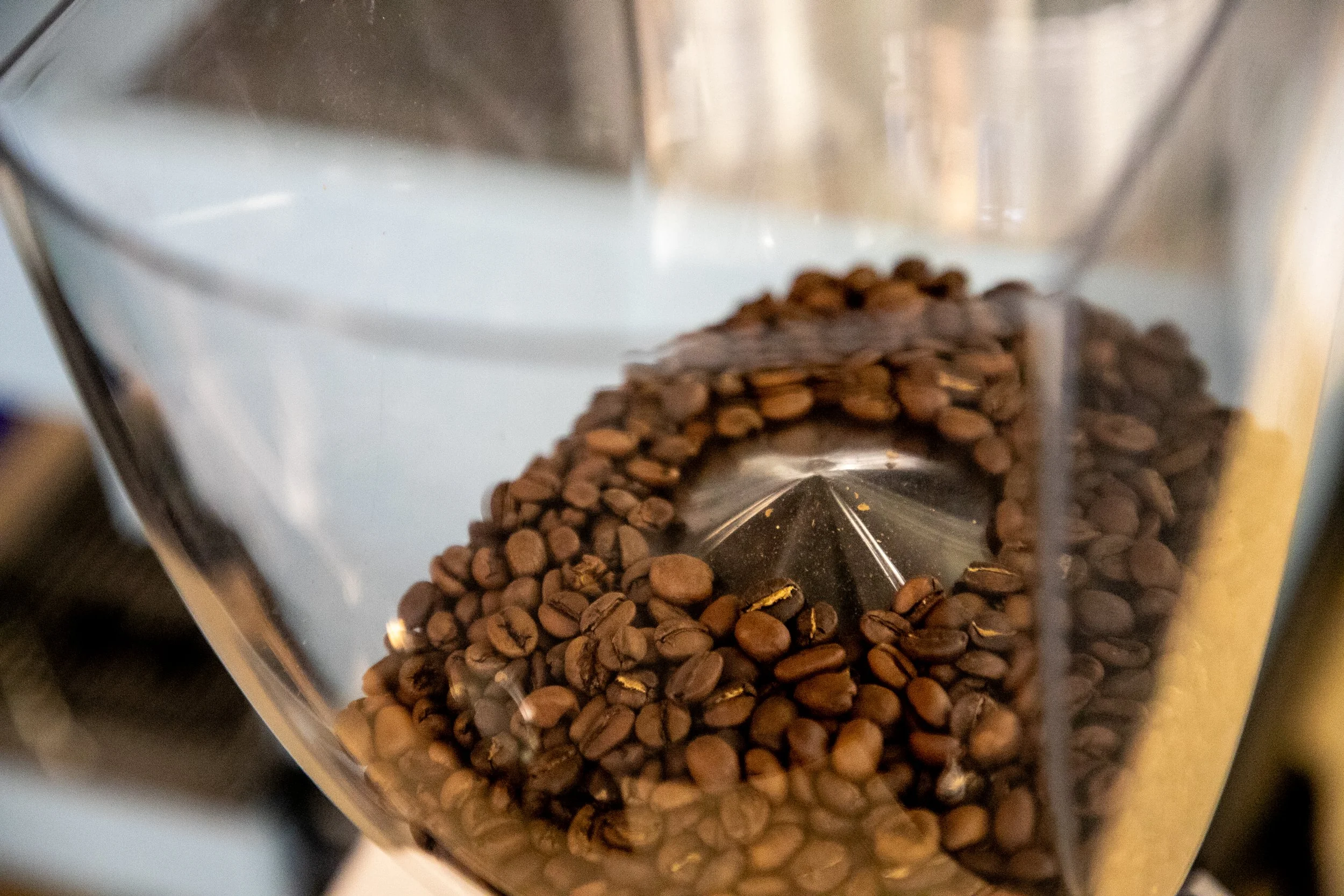 Close-up of coffee beans inside a metallic coffee grinder.
