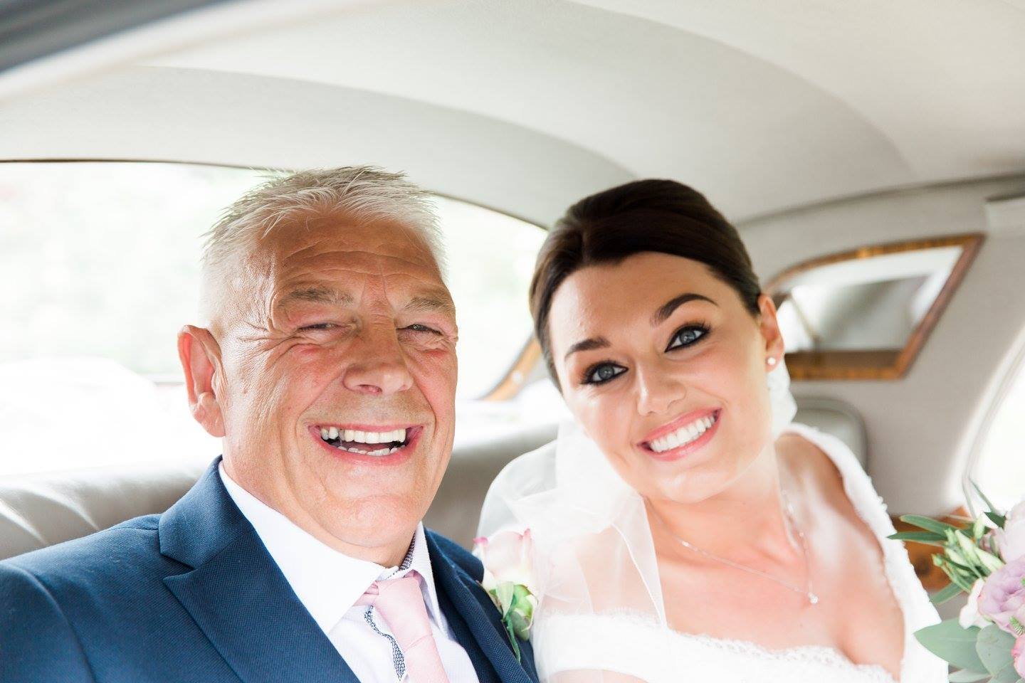 Smiling bride and groom in wedding car posing for a photo