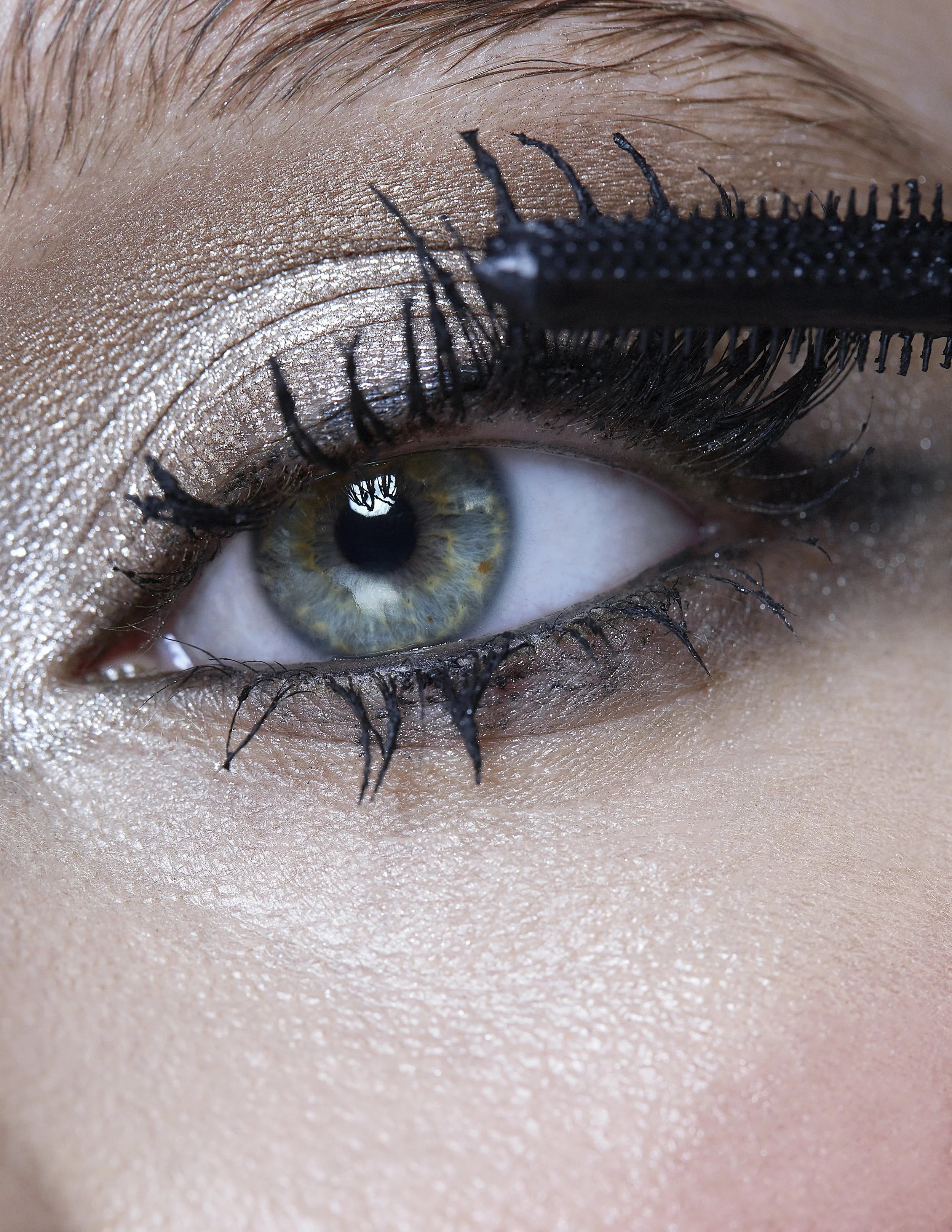 Close-up of an eye with makeup, including eyeshadow, mascara, and eyeliner, with the person's skin visible around the eye.