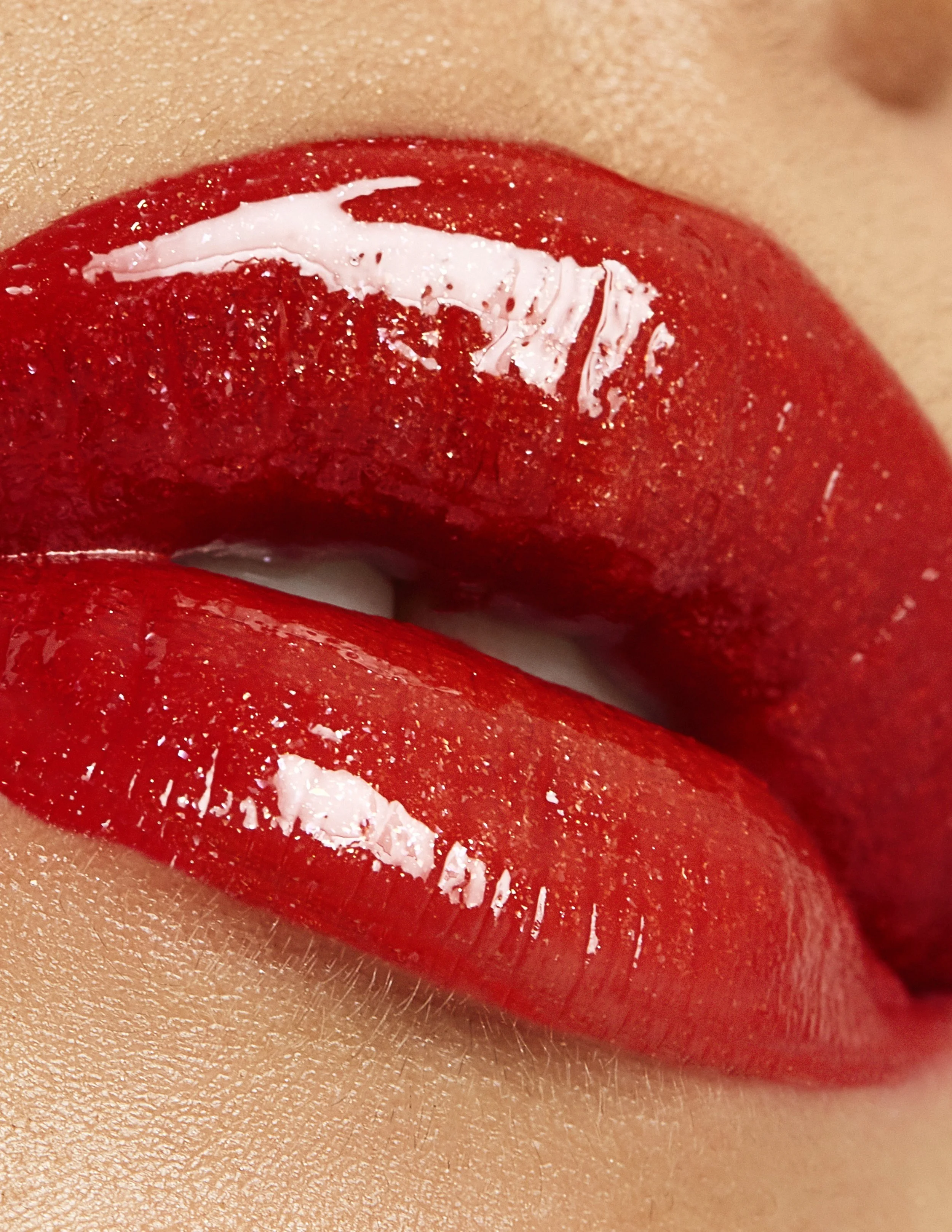 Close-up of lips with shiny red lipstick.