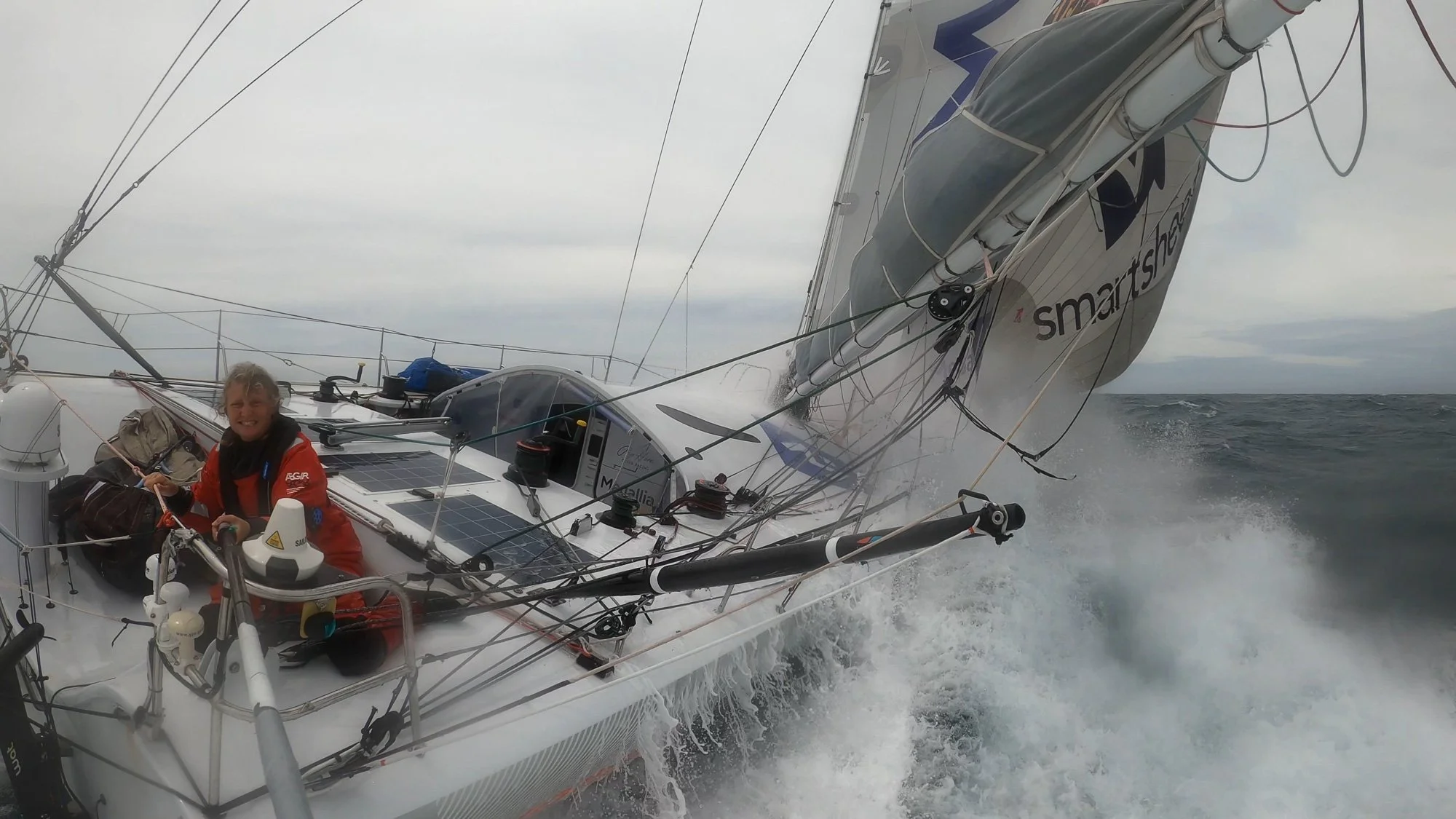 Pip Hare Ocean Racing sailor racing in rough seas as the yacht heels and waves break over the deck. Vendee Globe.