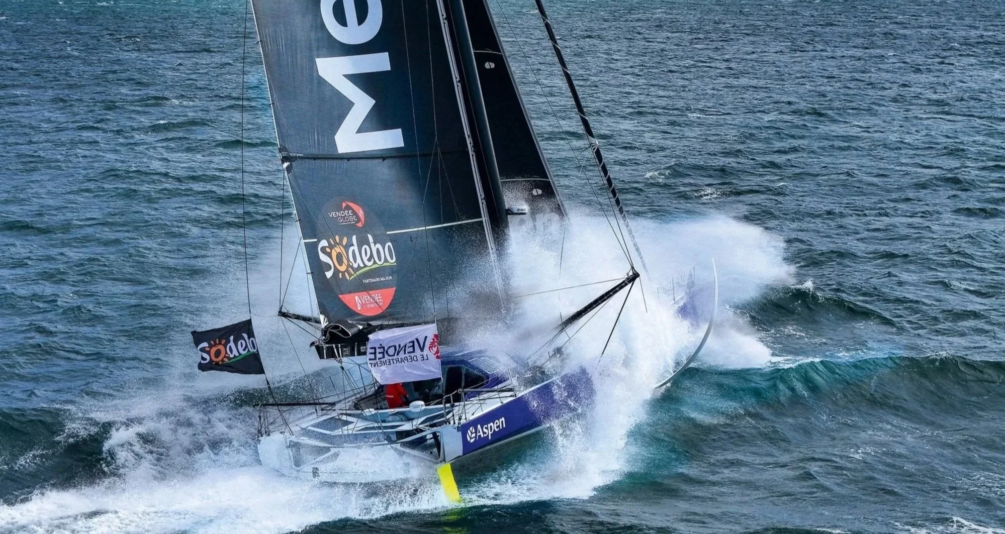 Pip Hare Ocean Racing, IMOCA sailing yacht. An offshore racing yacht with black sails cutting through waves at speed.