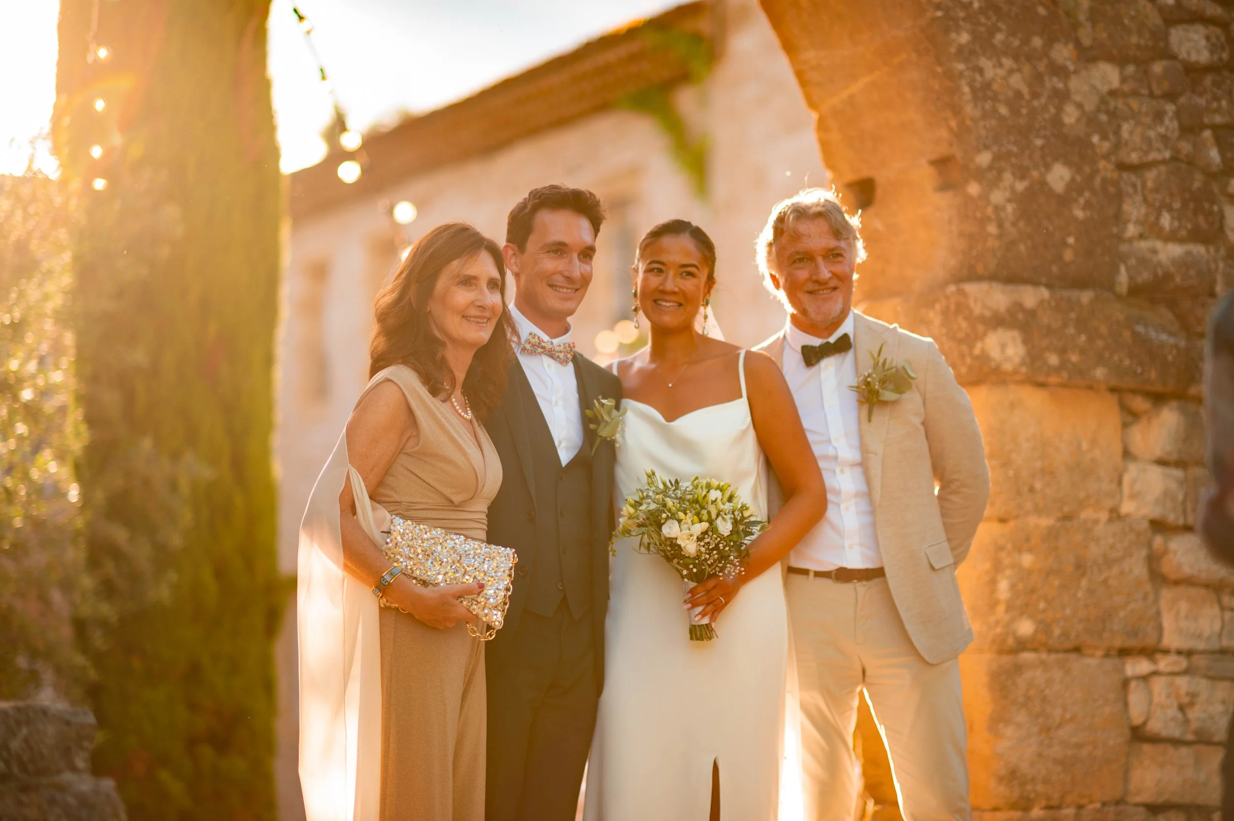 Groupe de cinq personnes lors d'un mariage en plein air à la tombée du jour, avec un fond de vieux murs en pierre et une lumière dorée