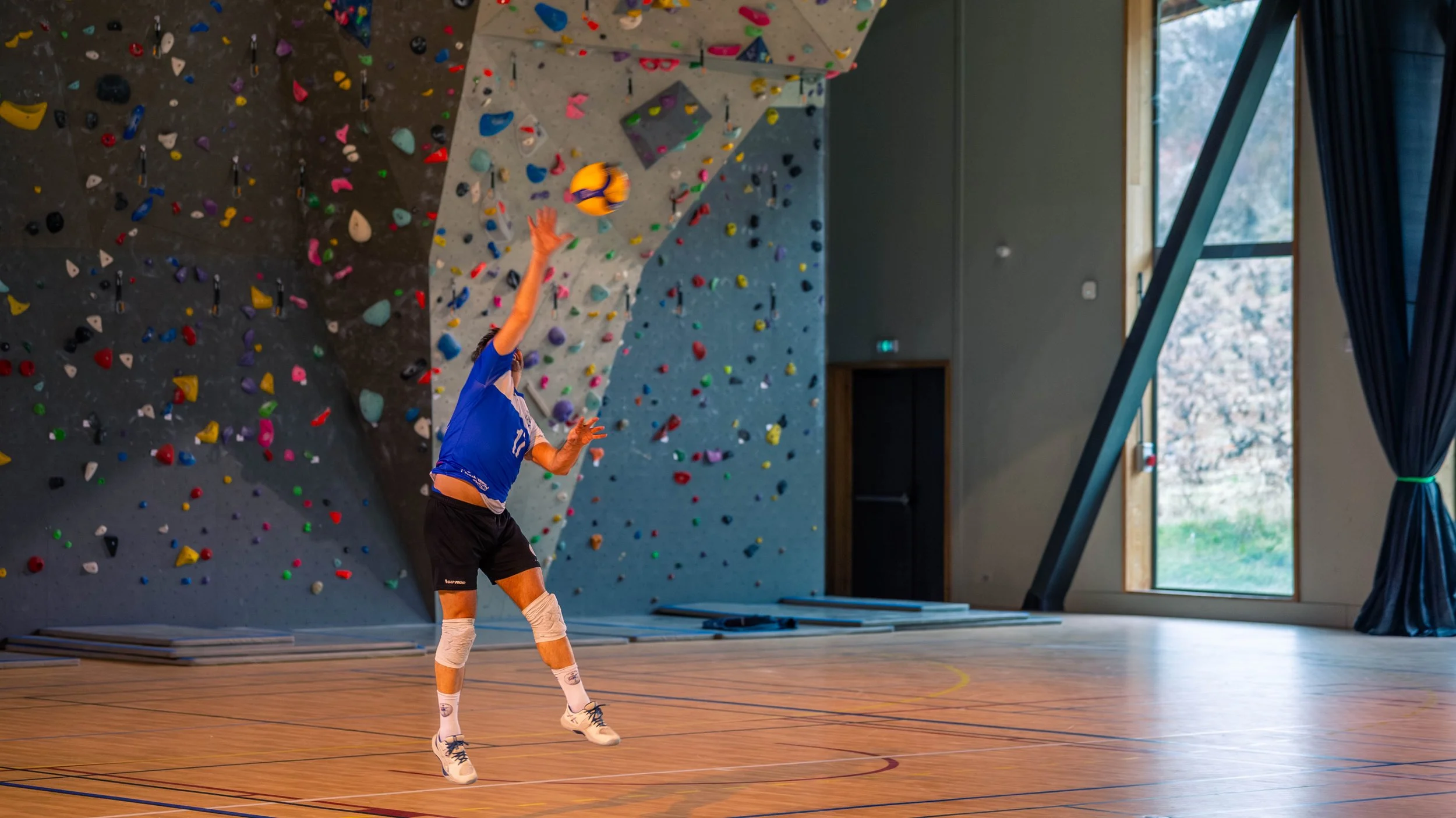 Un joueur de volleyball en train de faire un smash dans une salle d'escalade indoor.
