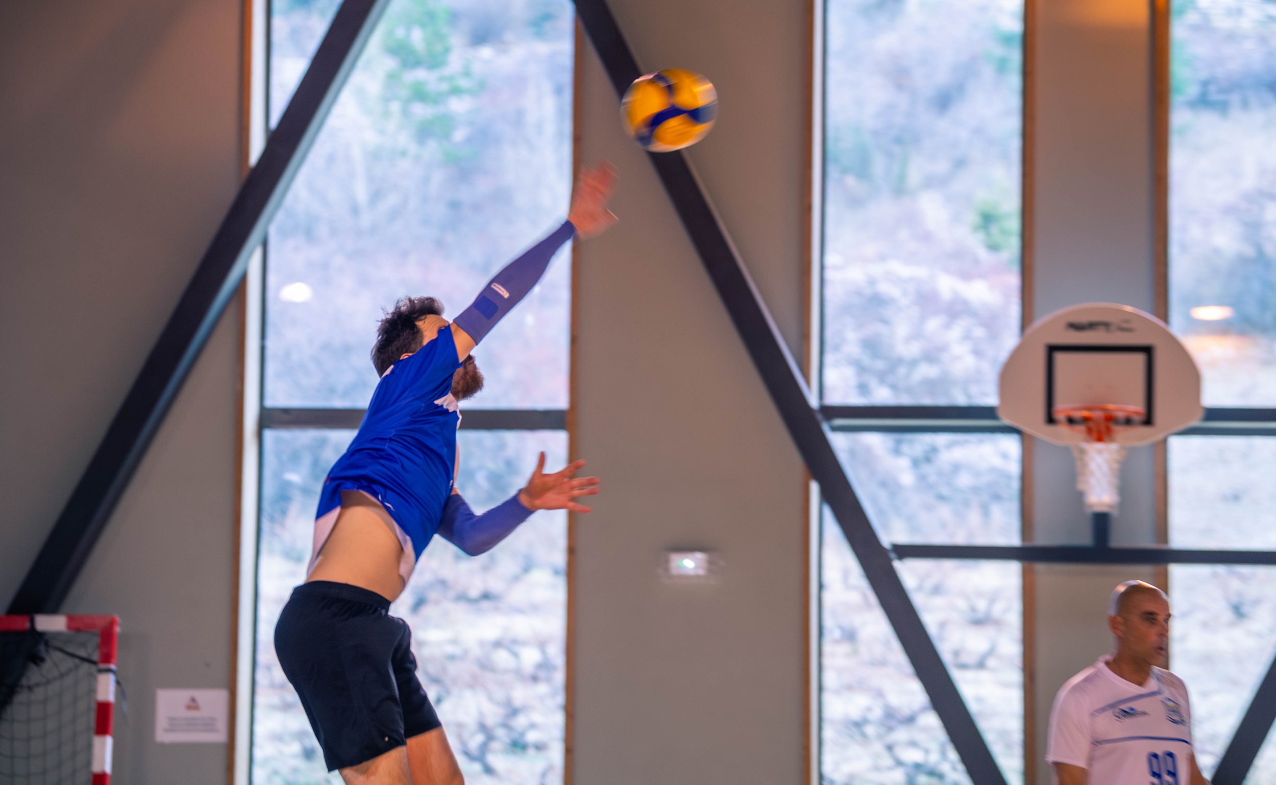 Un joueur de volley-ball en train de sauter pour frapper le ballon dans une salle de sport.