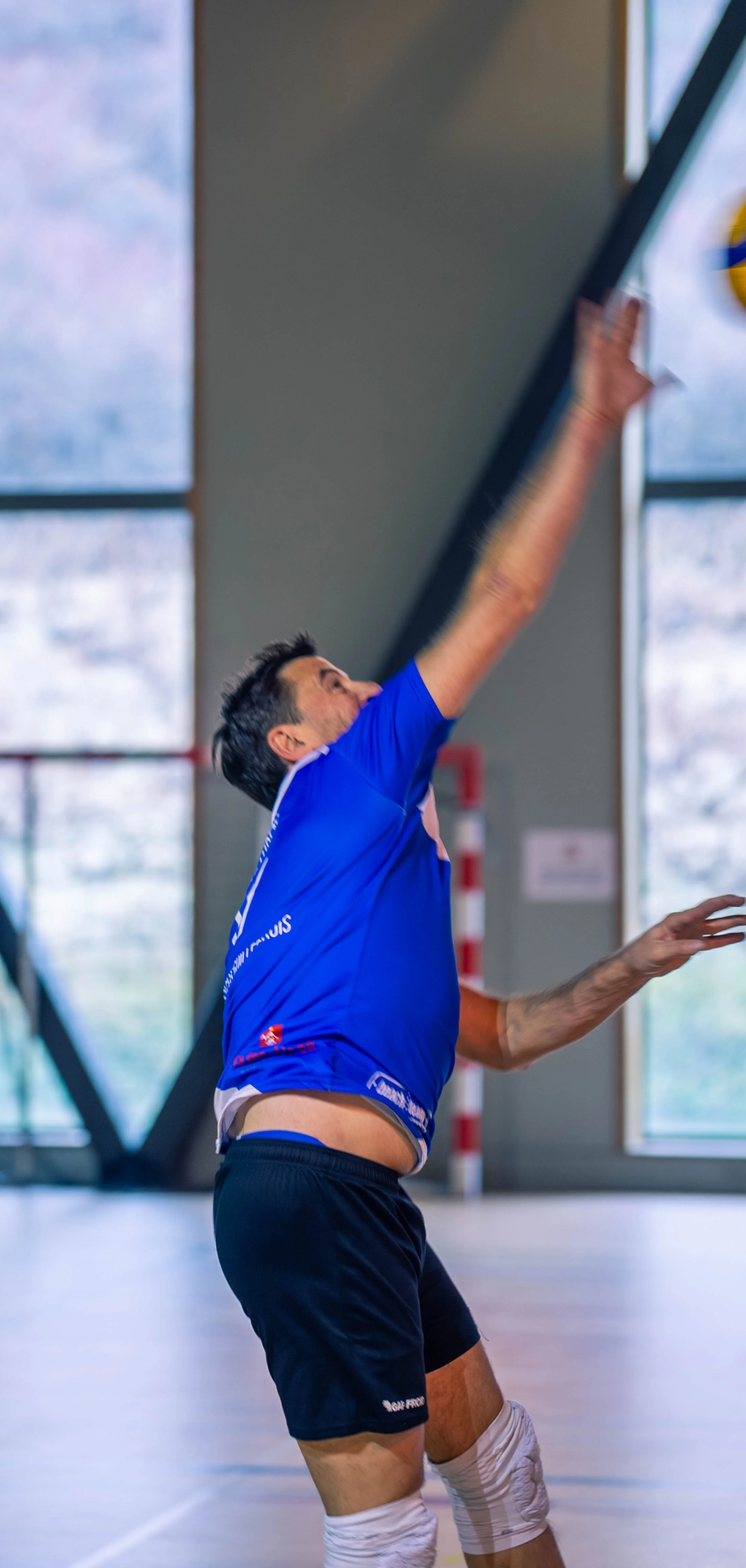 Un joueur de volleyball en train de sauter et de frapper le ballon dans une salle d'intérieur.
