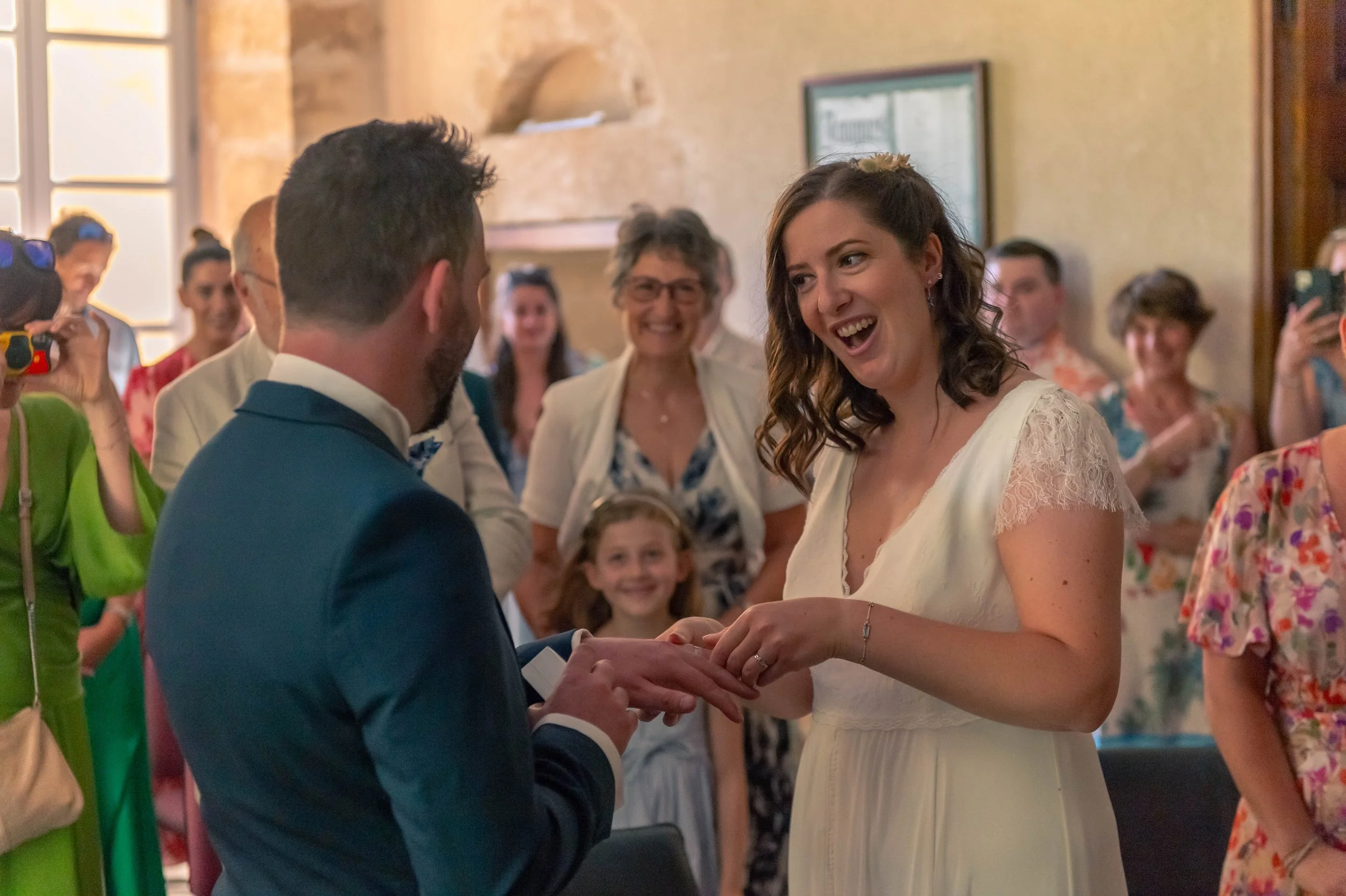 Une cérémonie de mariage avec un couple échangeant des alliances, entouré de famille et amis.