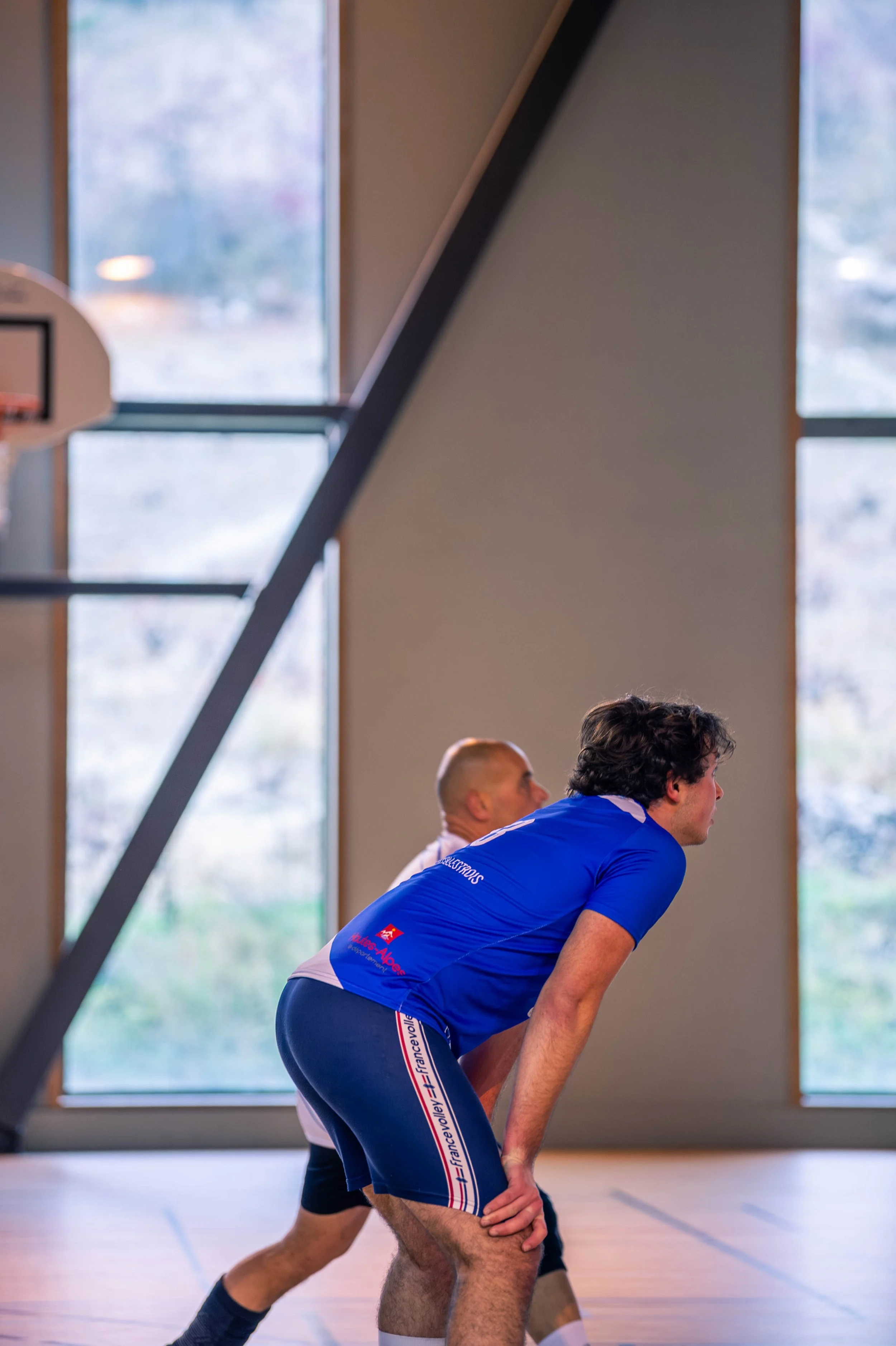 Deux hommes en tenue de sport dans une salle de sport, adoptant une position prête à courir ou faire un exercice.