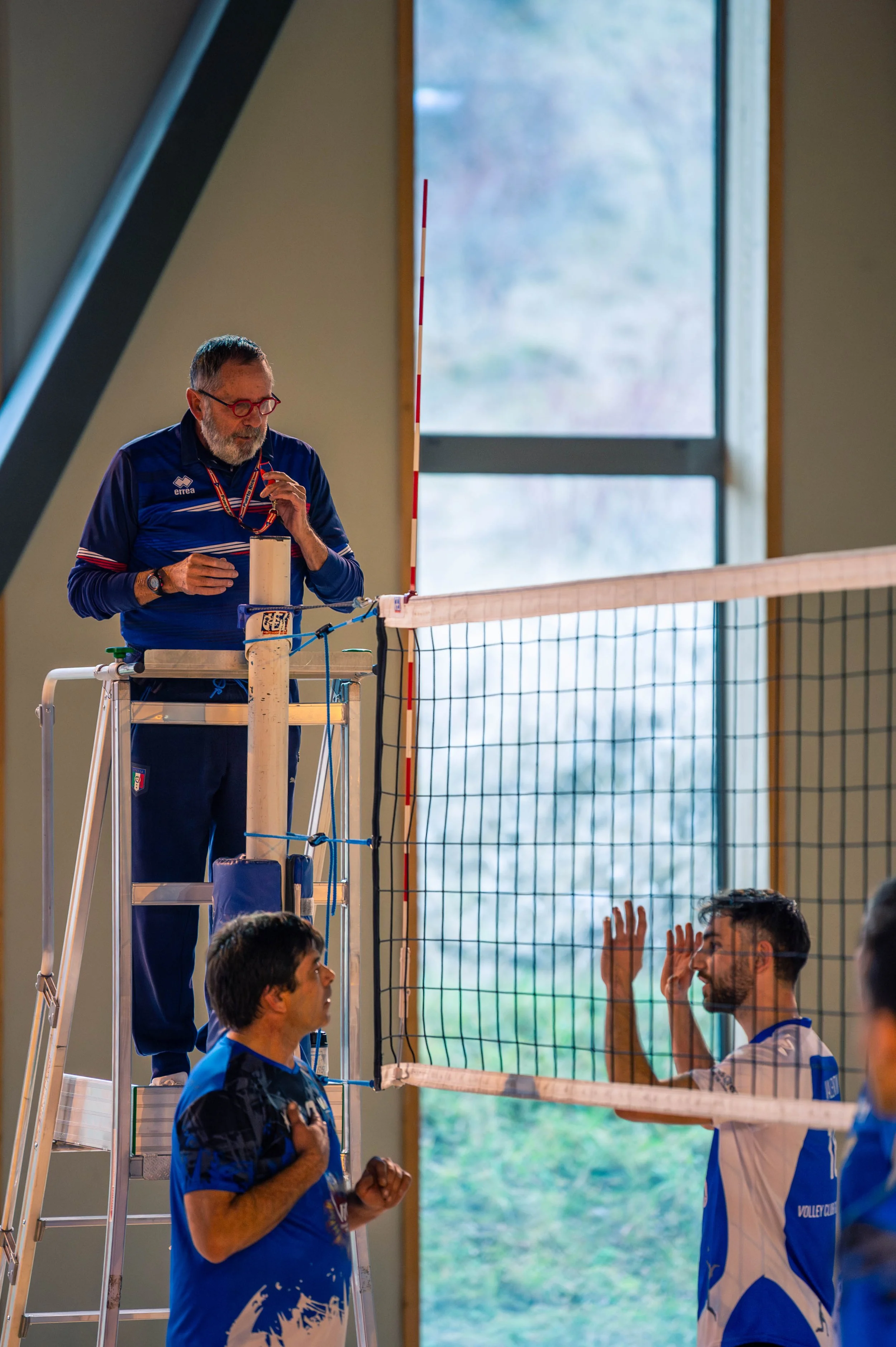 Un arbitre et deux joueurs lors d'un match de volleyball à l'intérieur