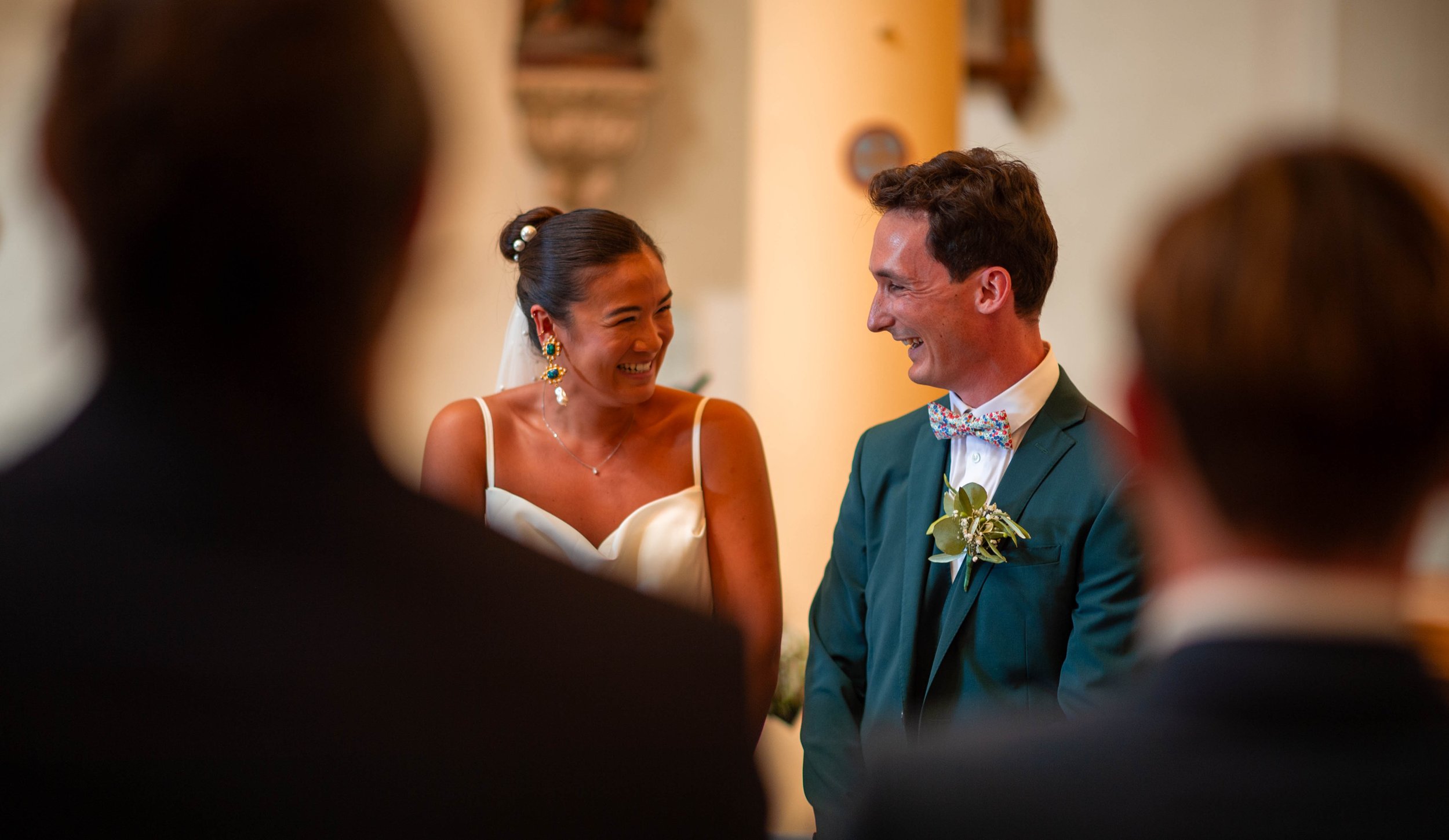 Un couple marié souriant lors de leur cérémonie de mariage, entouré d'invités.