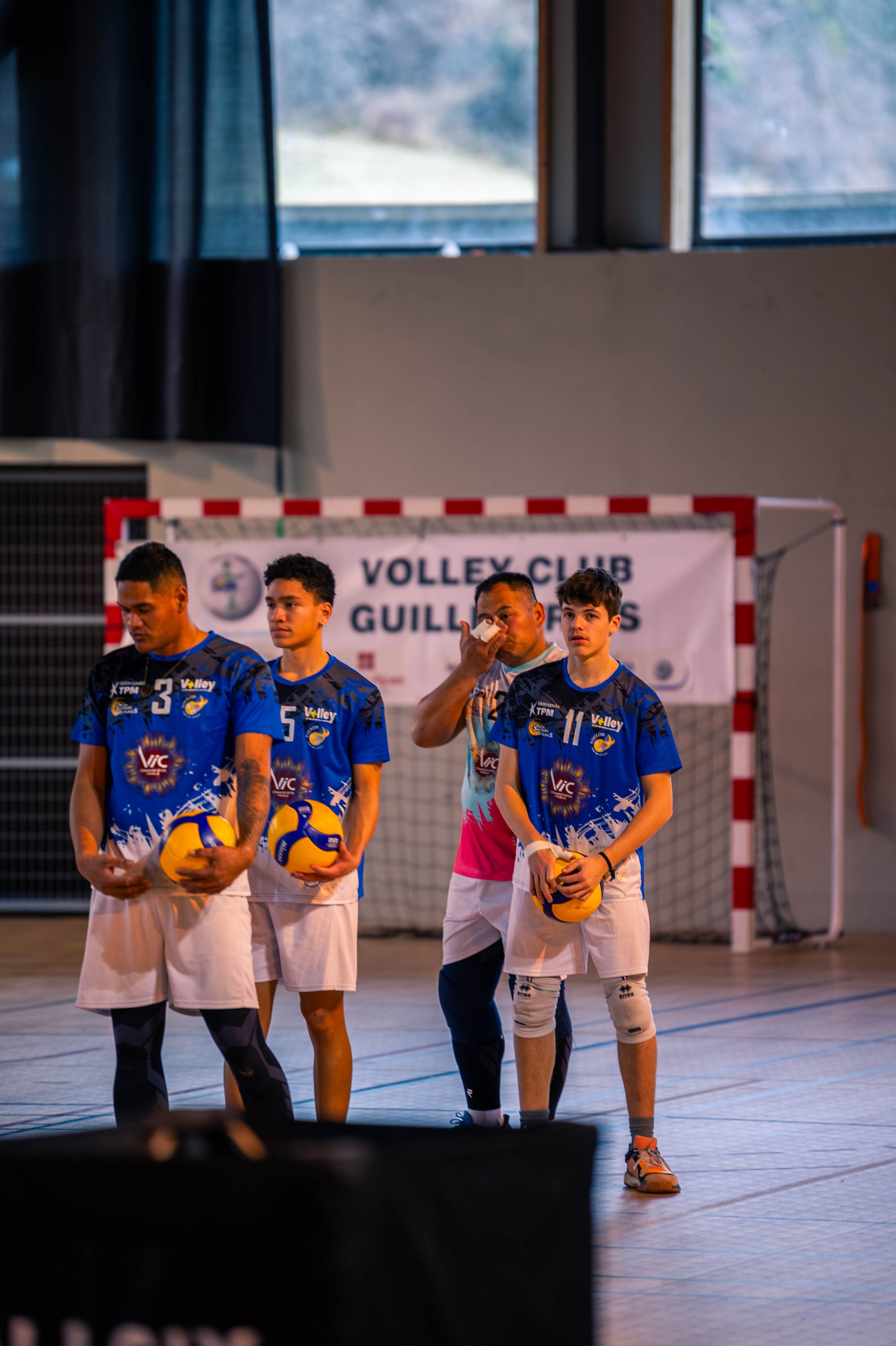 Groupe de jeunes joueurs de volley-ball en uniforme dans une salle de sport, sur le terrain.