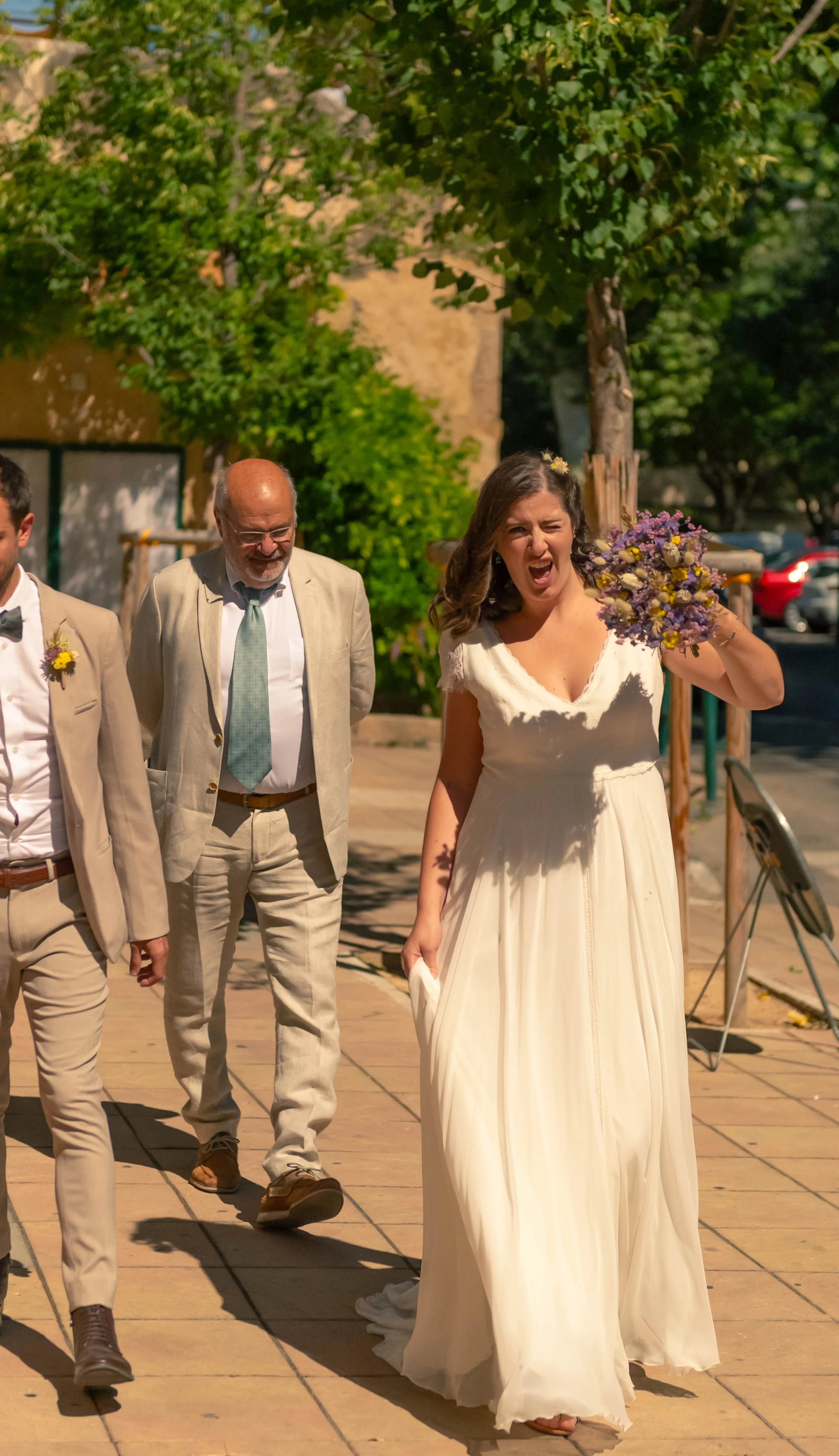 Une mariée en robe blanche joyeuse tenant un bouquet de fleurs en marchant.