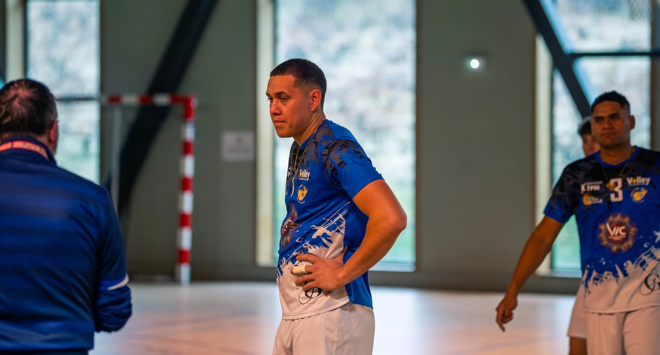 Joueur de sports en tenue bleue discutant avec un entraîneur dans une salle d'intérieur