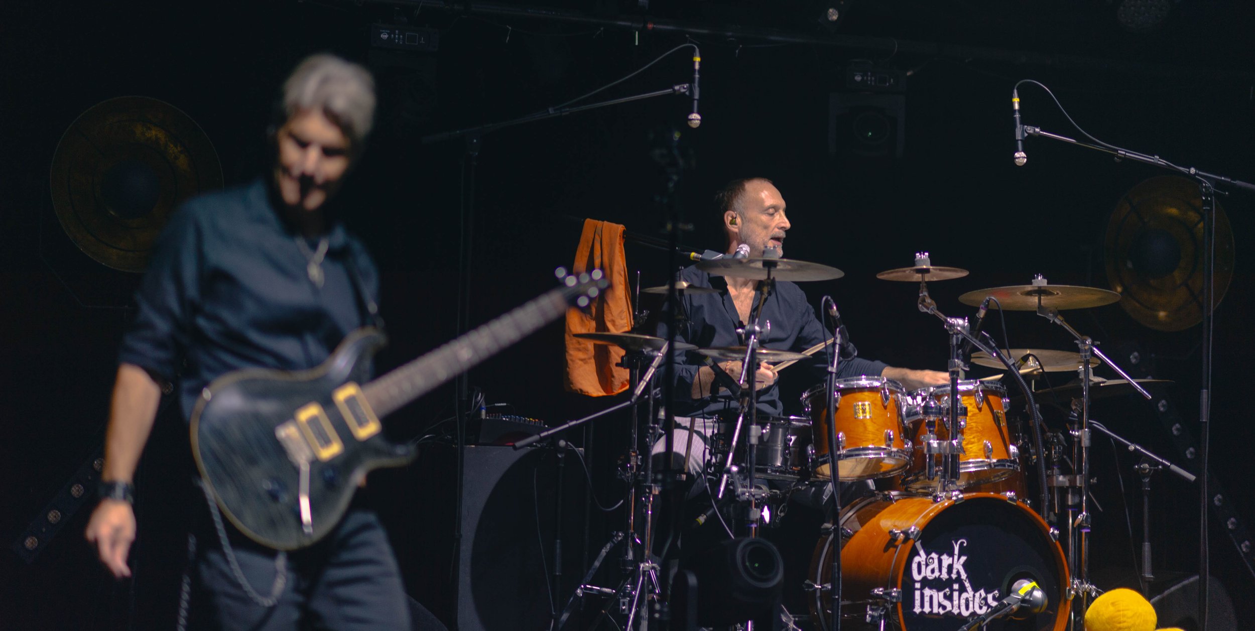 Deux musiciens en pleine performance sur scène avec un groupe nommé 'dark insides'.