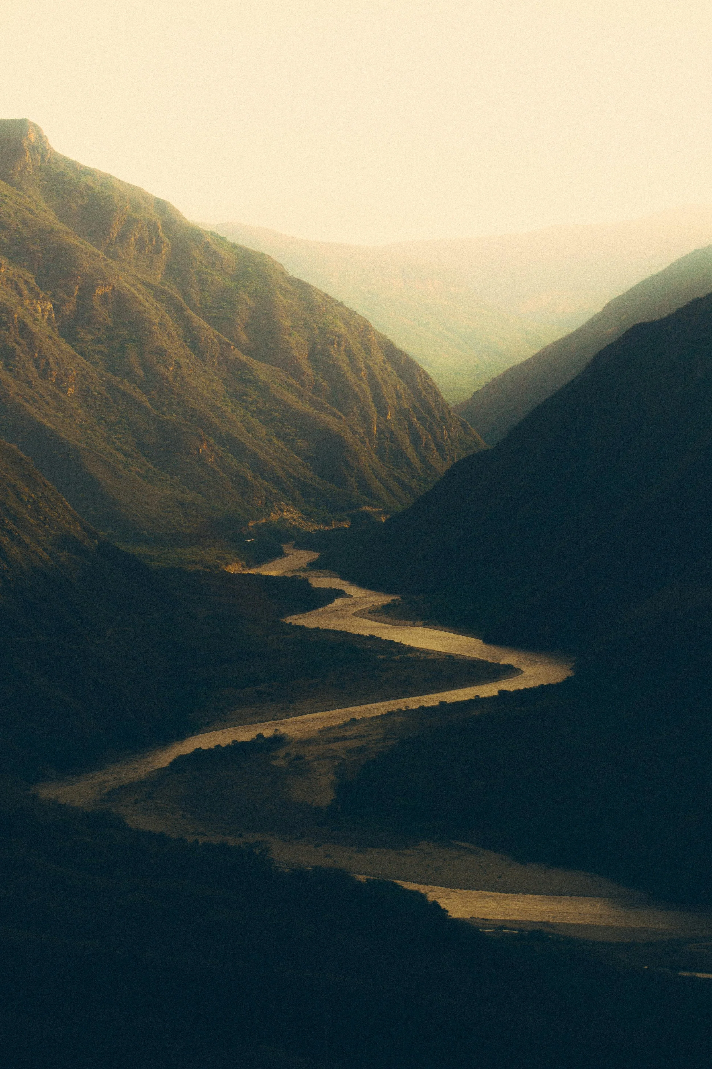 A winding river flows through a green mountain valley.
