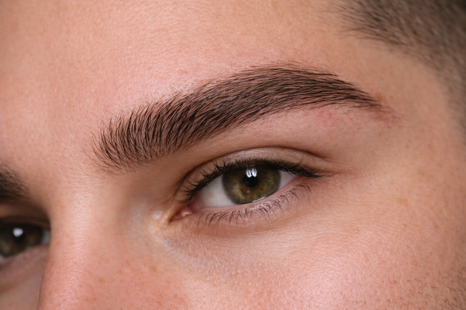 Close-up of natural male brow microblading hair stroke technique