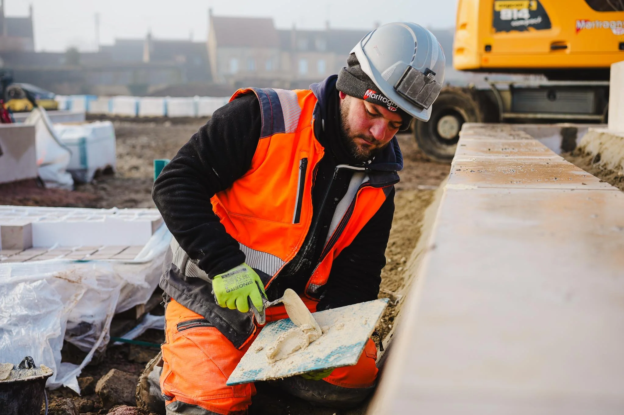 Maçon du BTP sur un chantier, équipé de ses protections, en train de faire des joints