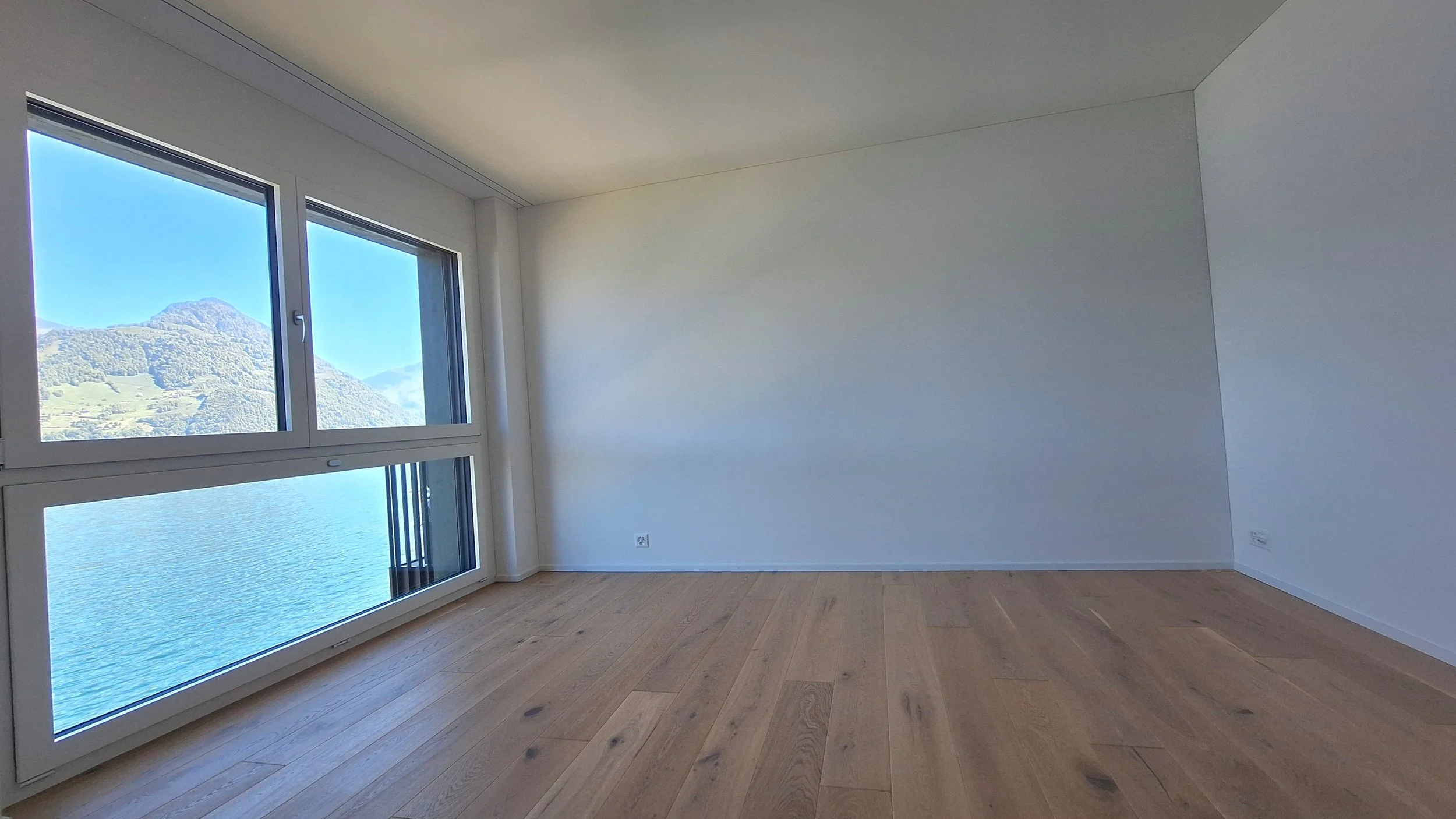 Ein Schlafzimmer mit einem Doppelbett, einem Schreibtisch mit Unterlagen und Stauraum, einem Fenster und einer Terrasse im Hintergrund.