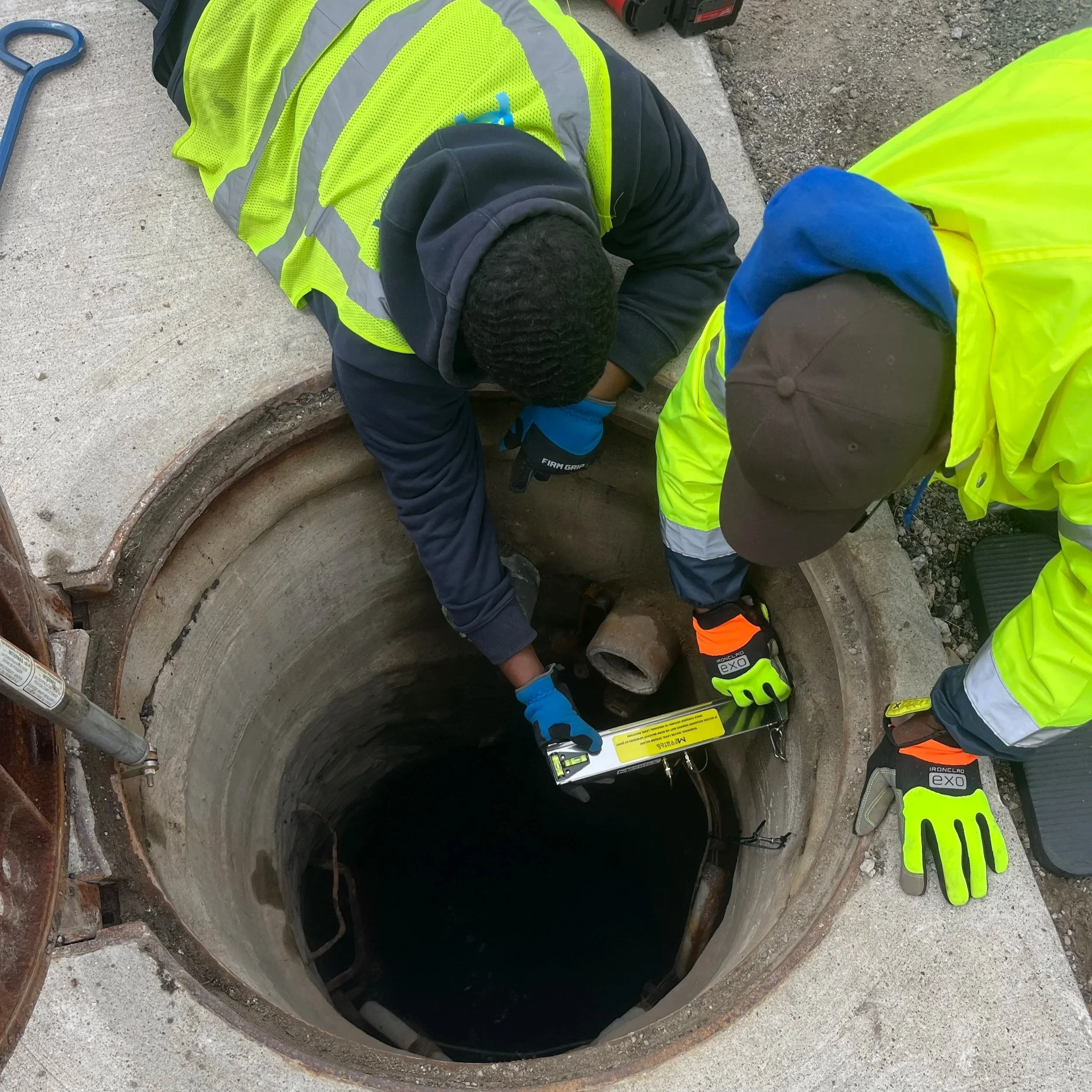 Utility staff installing ManholeMetrics wastewater level sensor inside  inside a sewer or drainage manhole.