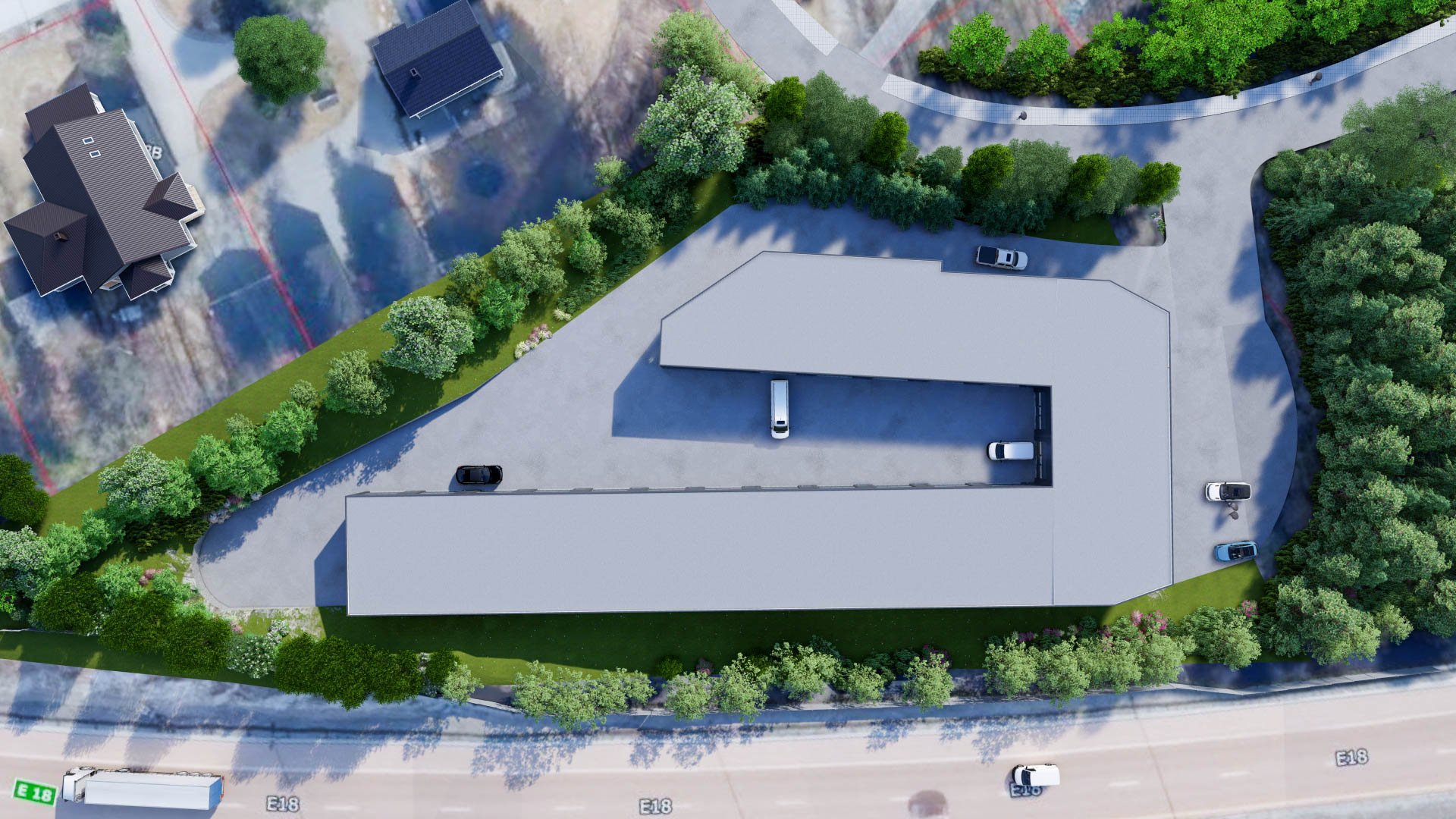 Aerial view of a large building complex with parking lot, surrounded by green trees, roads, and neighboring houses.