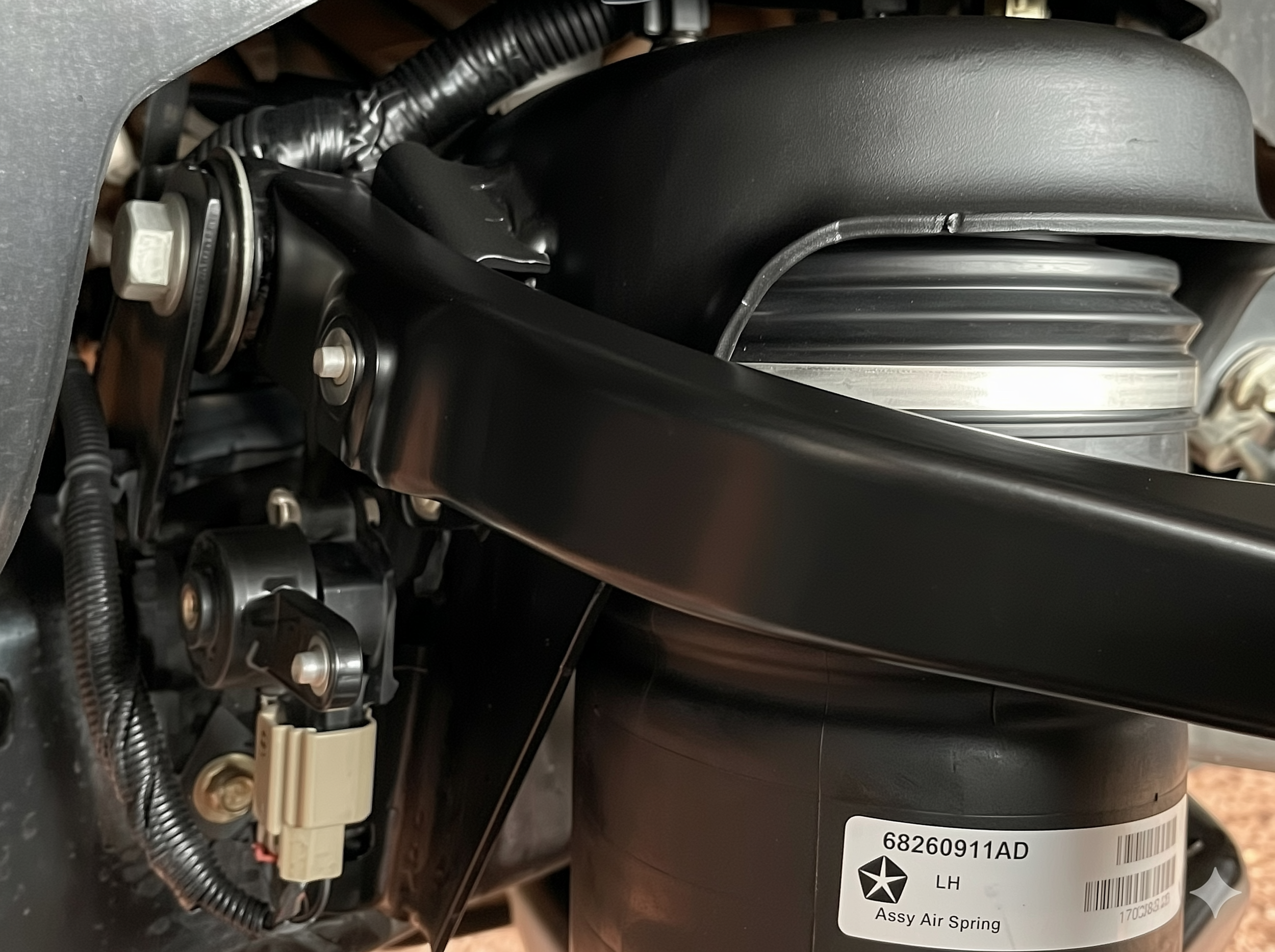 Close-up of lowering link mounted to Ram 1500 air suspension ride height sensor arm