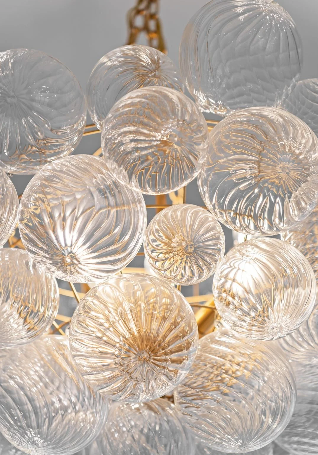 Close-up of a collection of glass decorative spheres with intricate patterns, reflecting light, set against a neutral background.