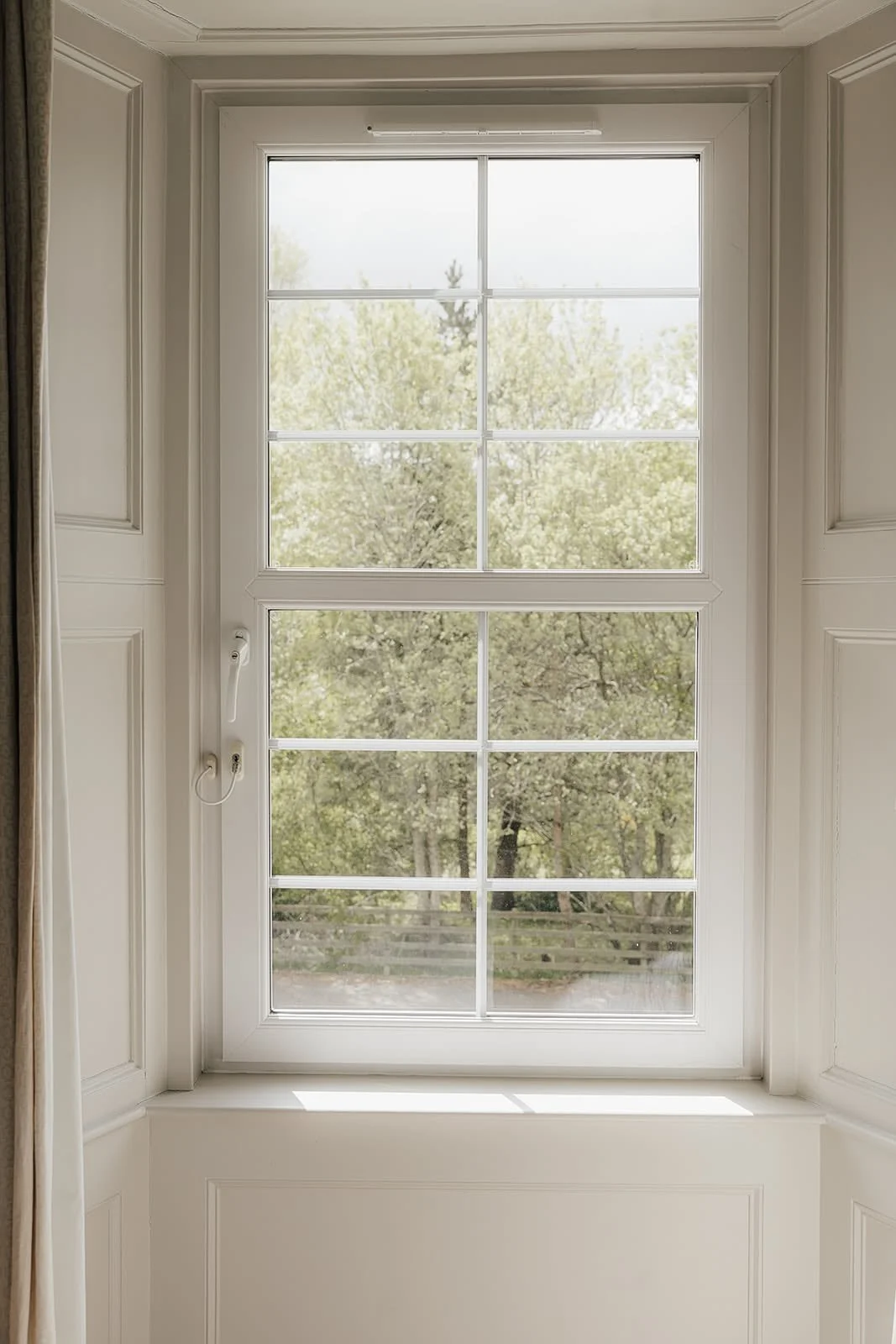 Tall white sash window letting soft light into a calm room at Dunalastair, Scotland
