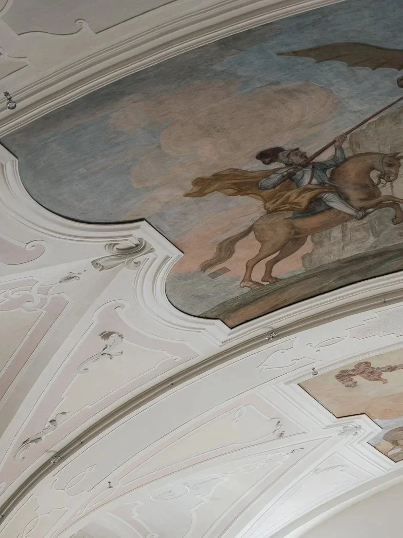 Deckenfresko mit einem Ritter auf einem Pferd und einem Drachen in einer barocken Kapelle.