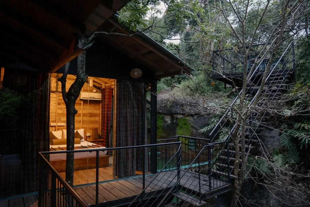 Wooden treehouse with a warmly lit room and an outdoor staircase among the trees at The Glenrock, Sri Lanka