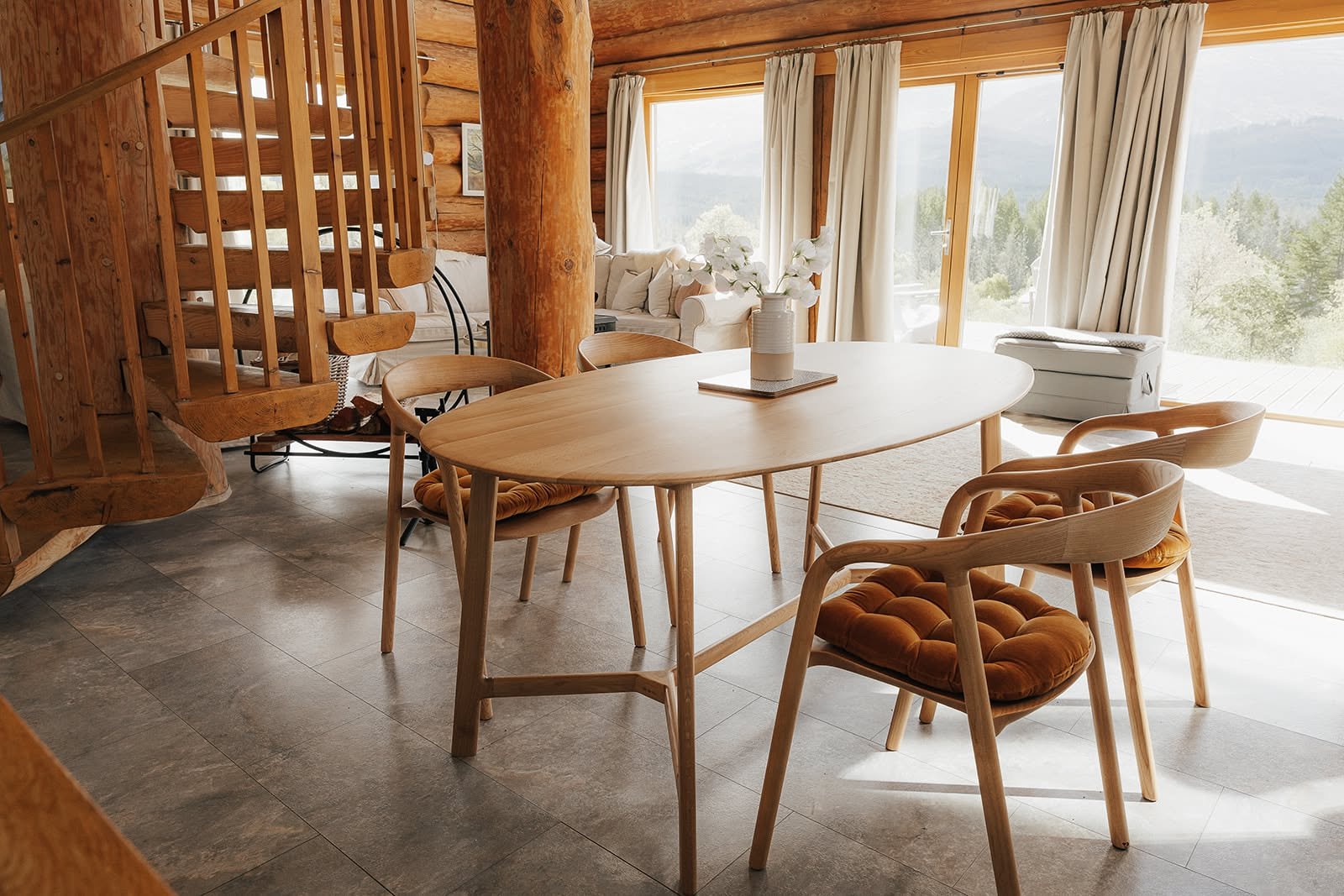 Sunlit wooden dining room with a spiral staircase and Highland views at Dunalastair, Scotland, during a WILD Nurture retreat