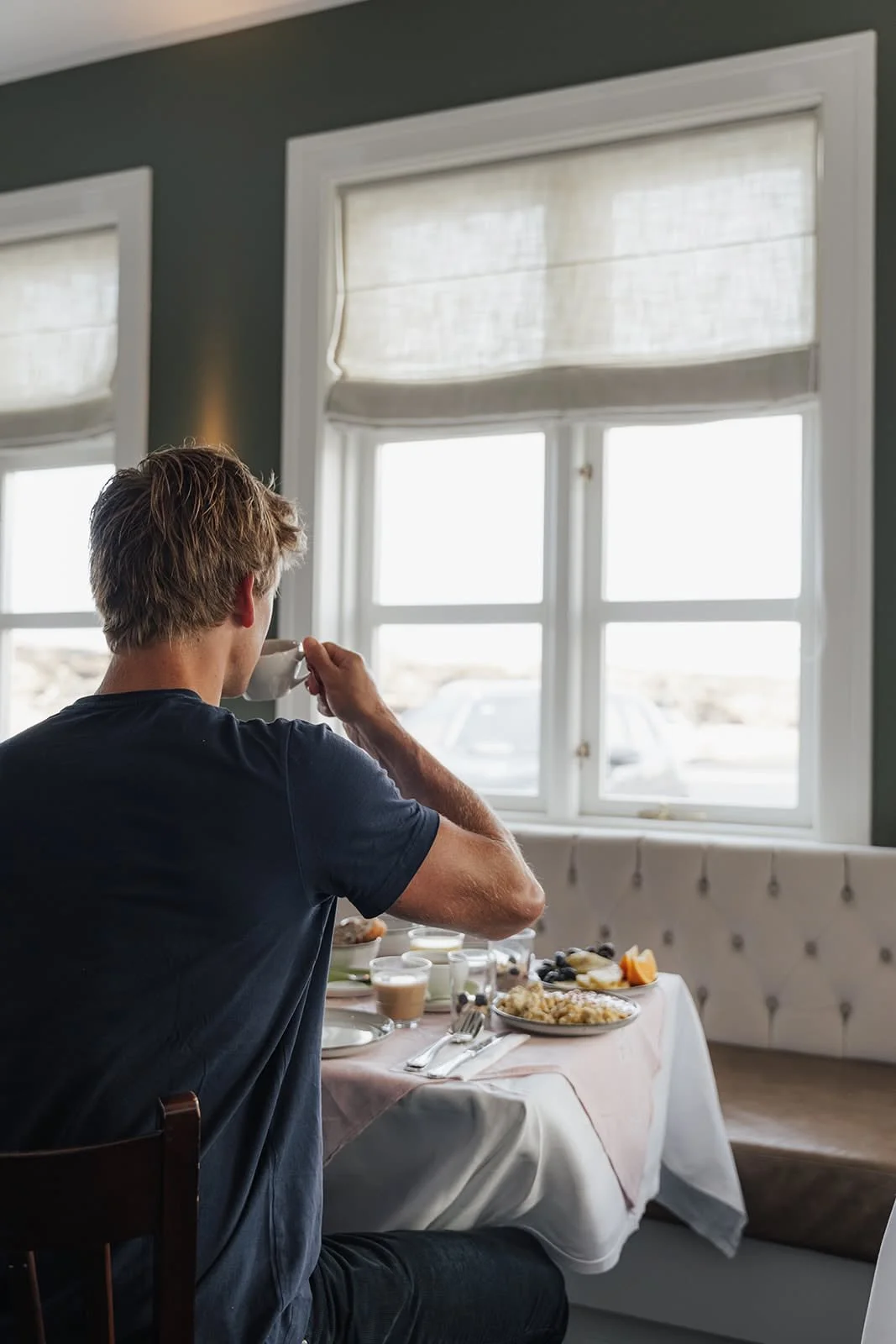 Man having breakfast at a white-clothed table by the window at Hótel Búðir, Iceland