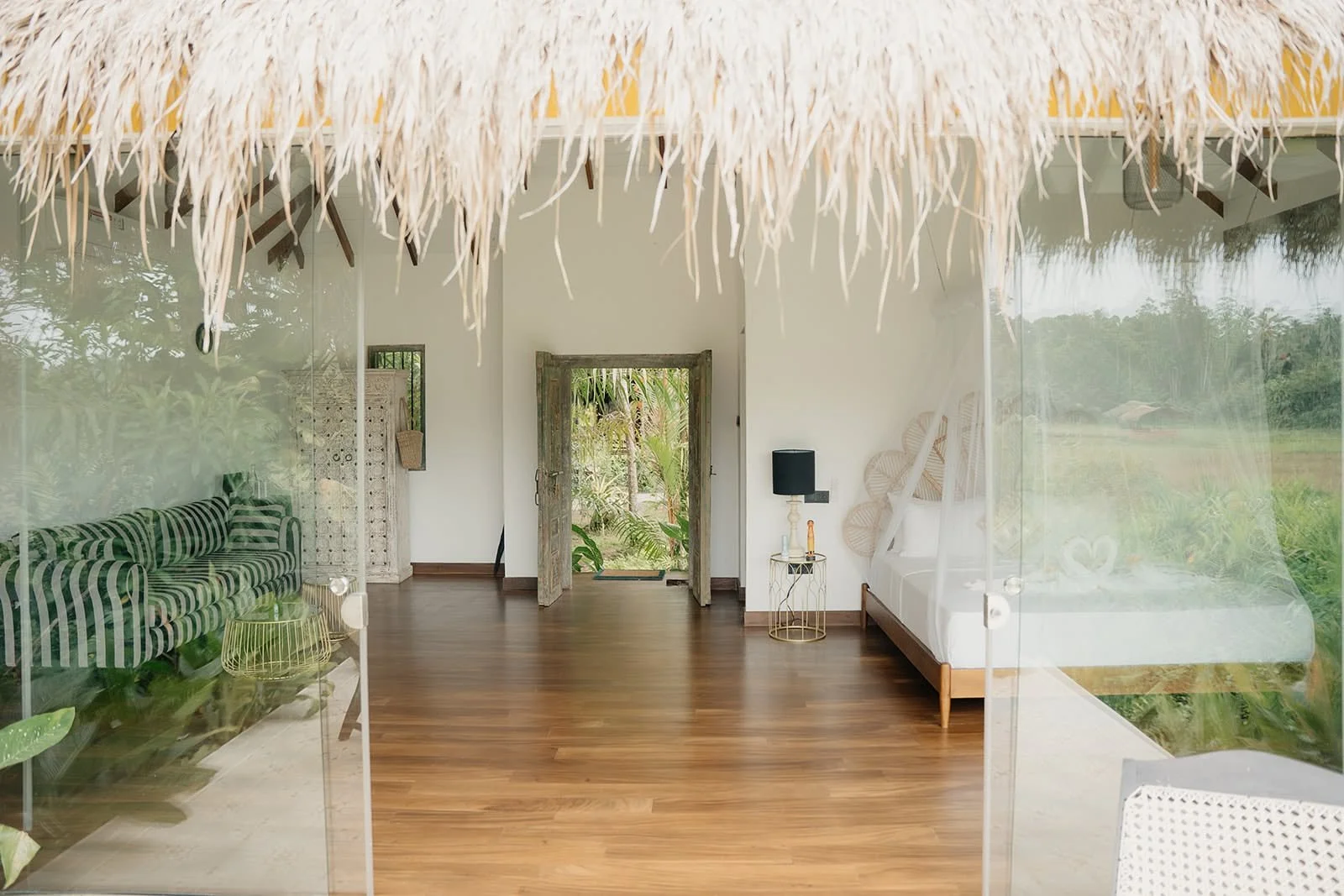 Bright bedroom with a thatched ceiling, wooden floor and a bed under a mosquito net at Huma Terra Lodge, Sri Lanka