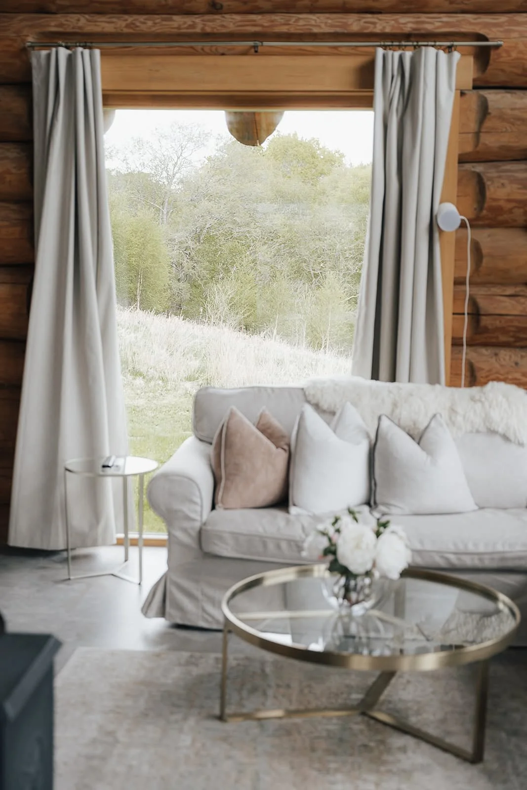 Cosy living room with a linen sofa, glass coffee table and garden window in a timber lodge at Dunalastair, Scotland