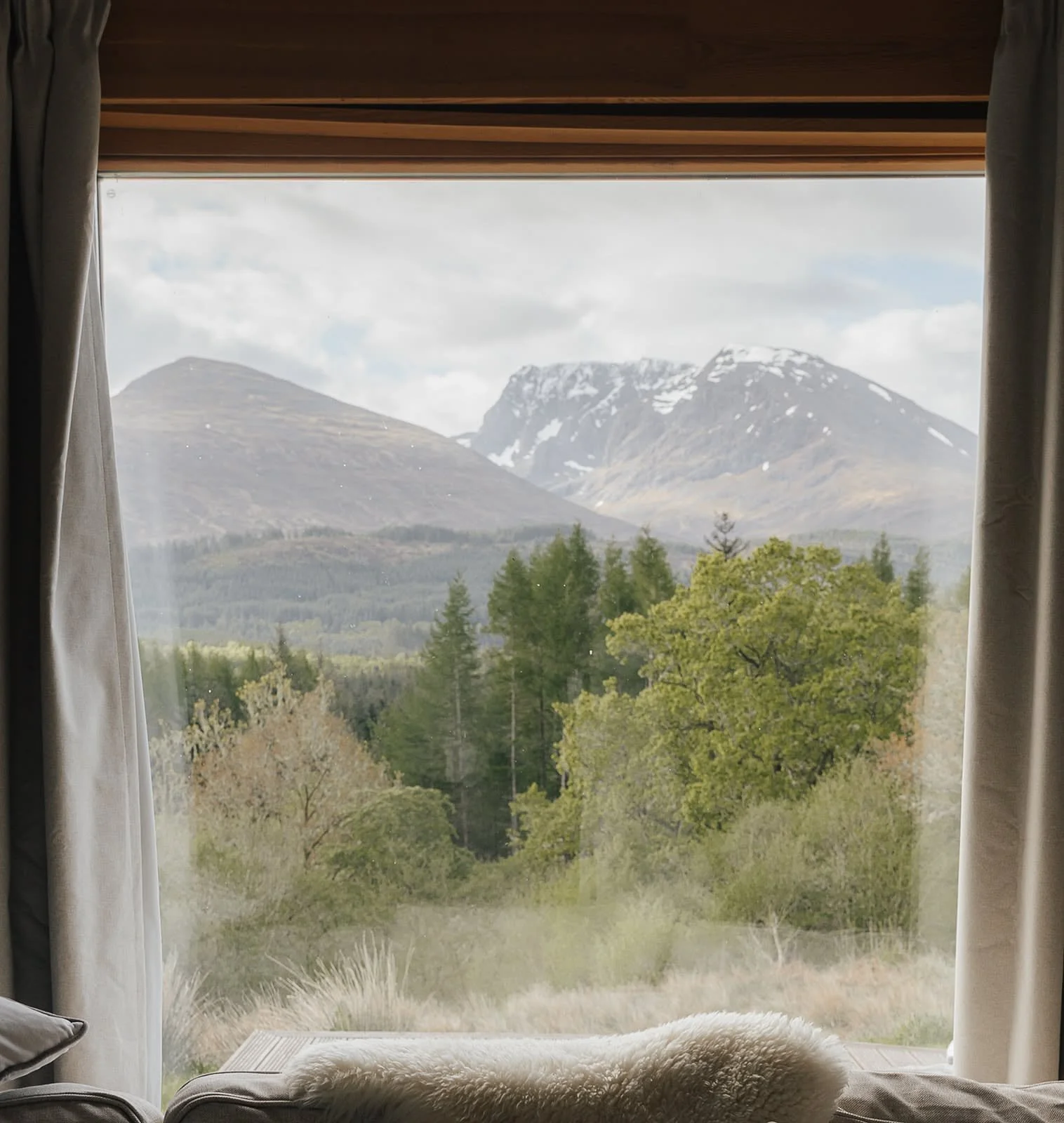 Window framing pine forest and snow-dusted Highland mountains at Dunalastair, Scotland