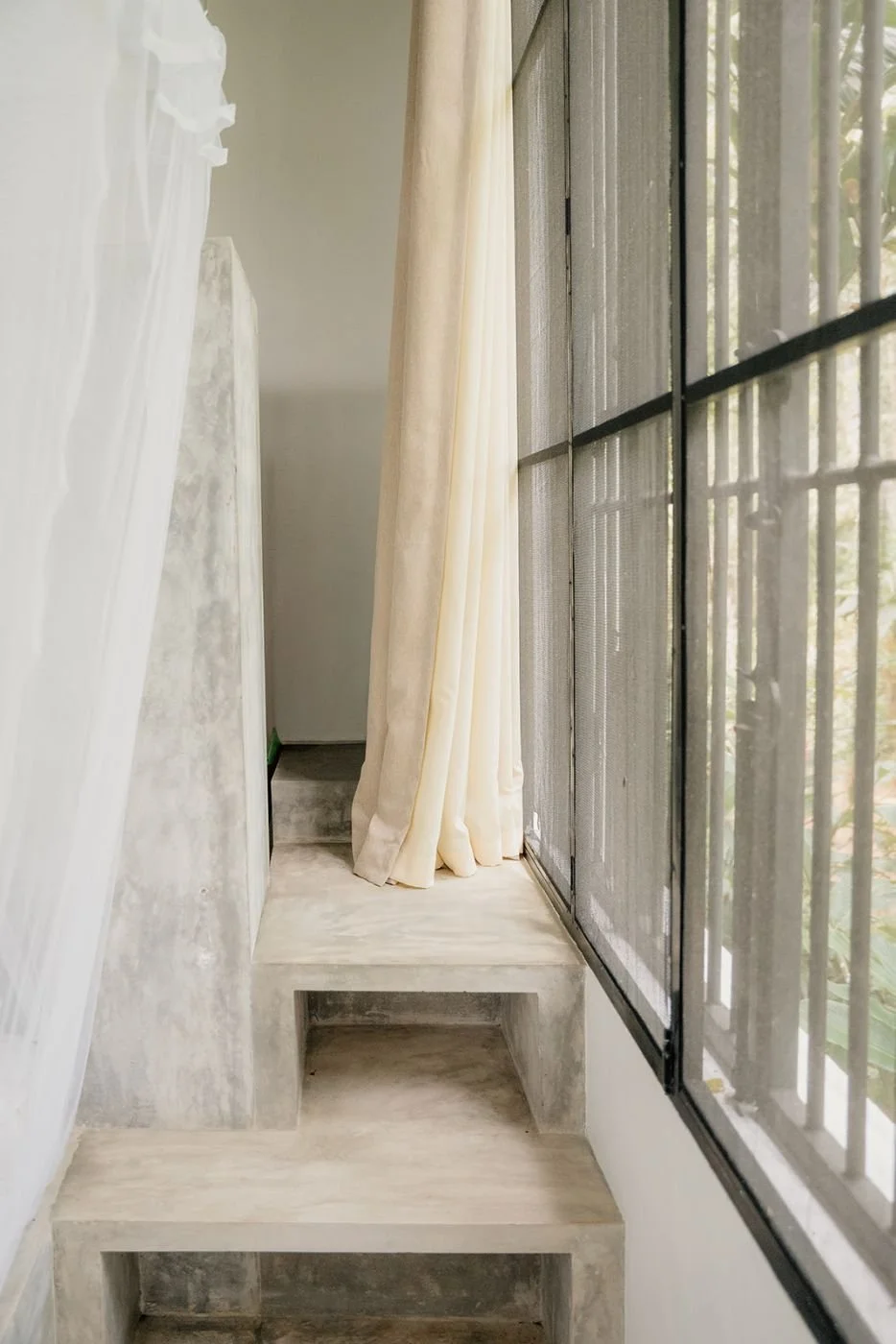 Light-filled hotel interior with linen curtains and stone steps – spaces and interiors photography by Anna van der Veen