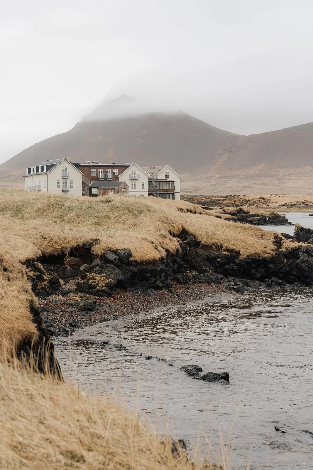 Hótel Búðir standing alone on the Snæfellsnes coast in Iceland, with lava rocks and misty mountains behind